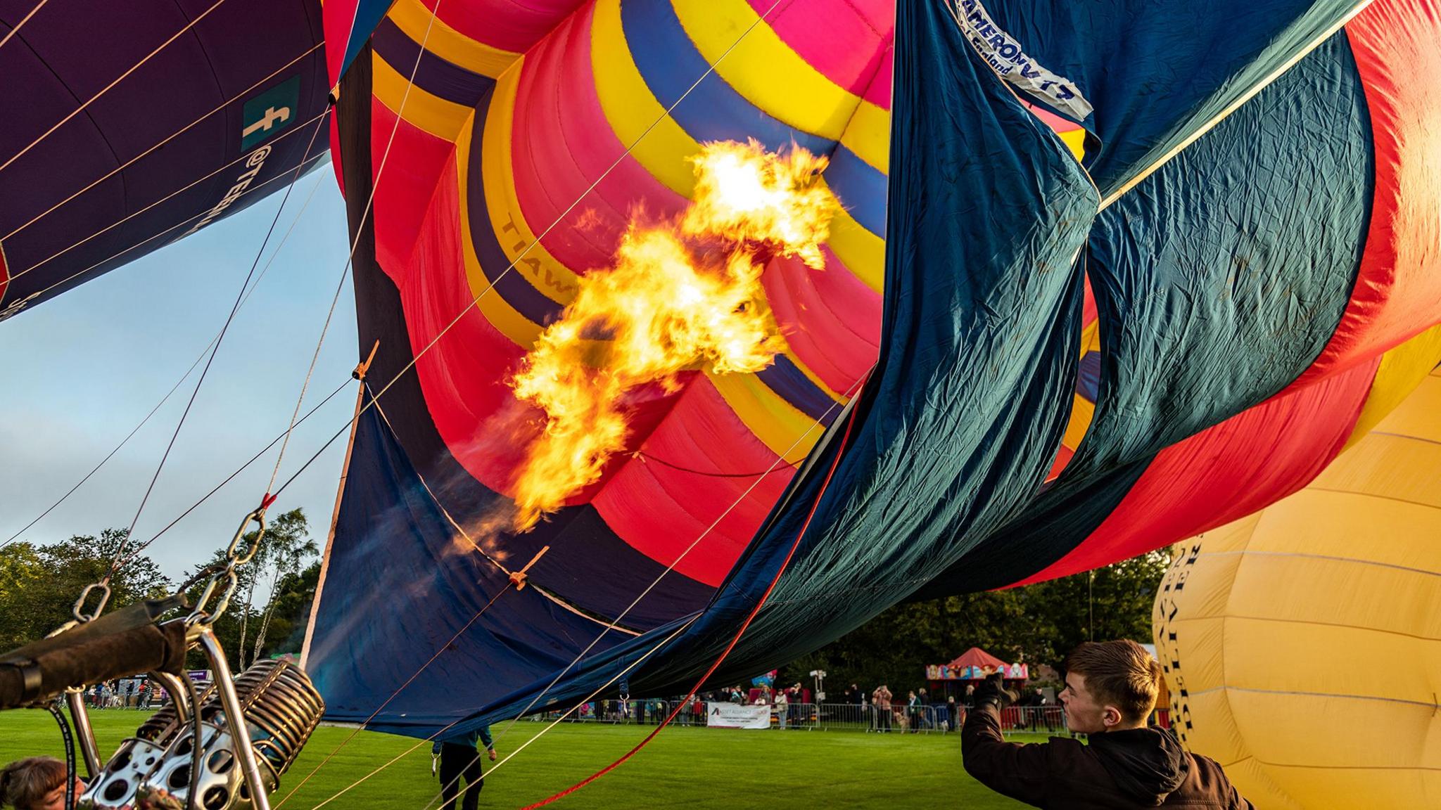 A burner inflates a hot air balloon tethered to the ground