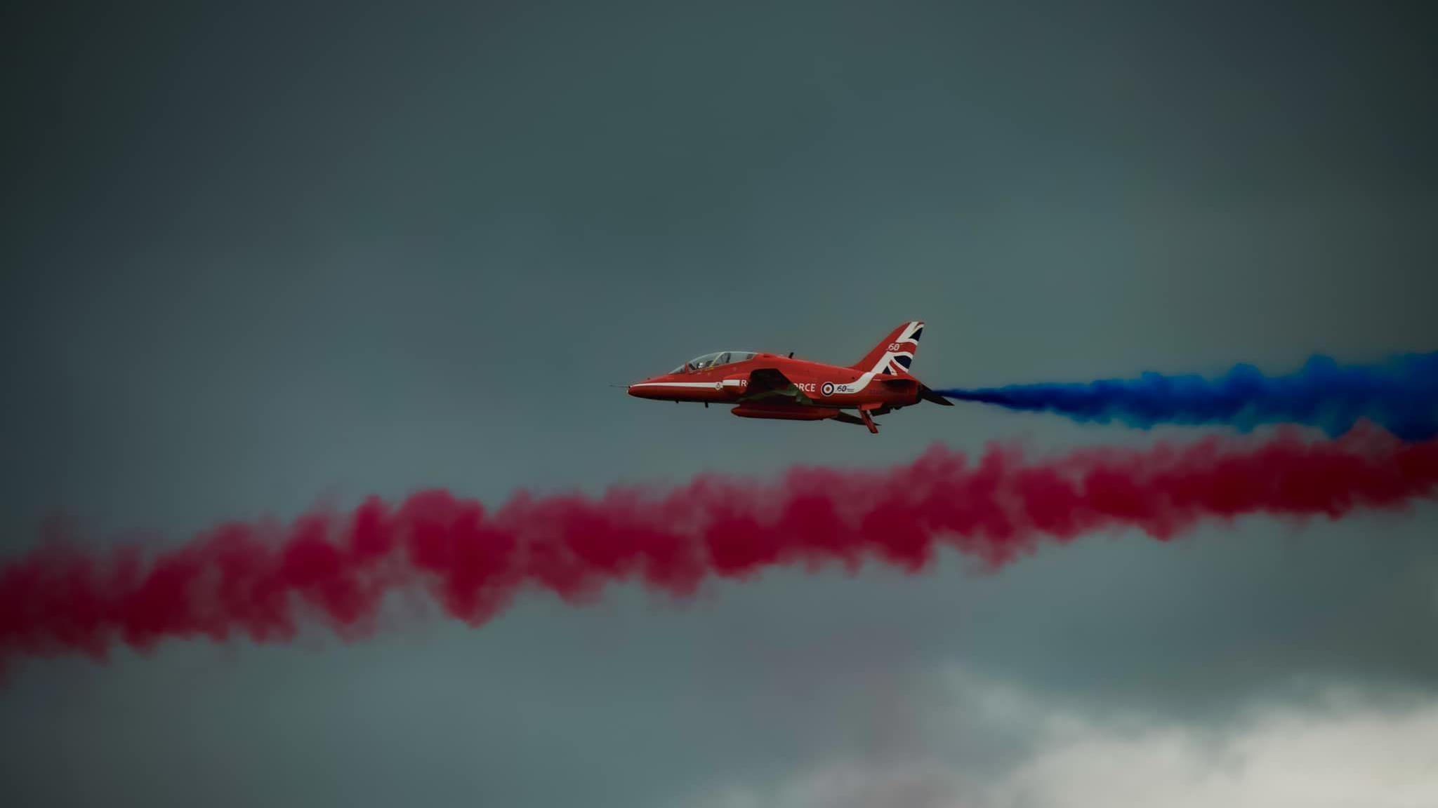 A red arrow in the sky, trailing blue smoke