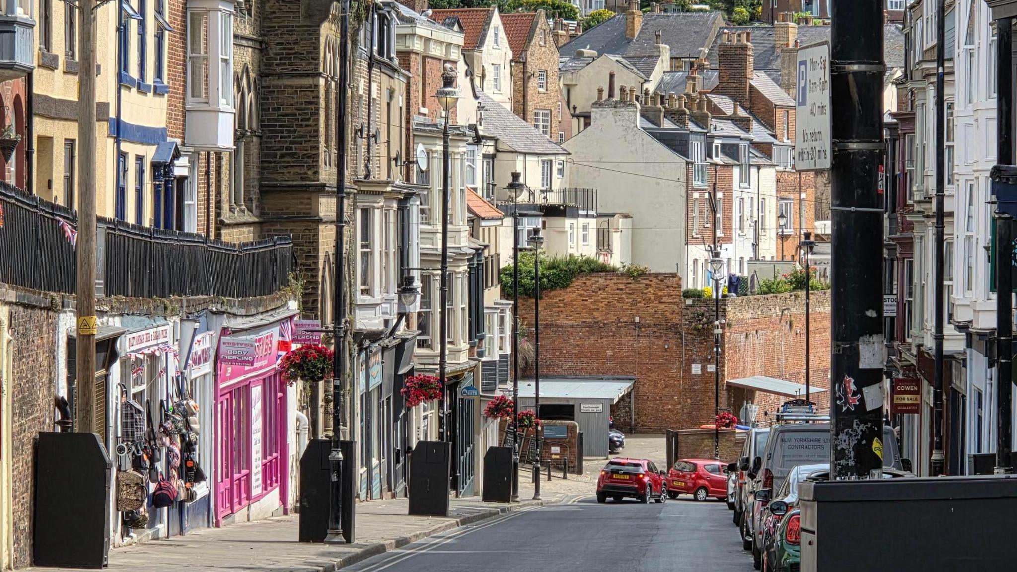 A coastal street lined with black bins.