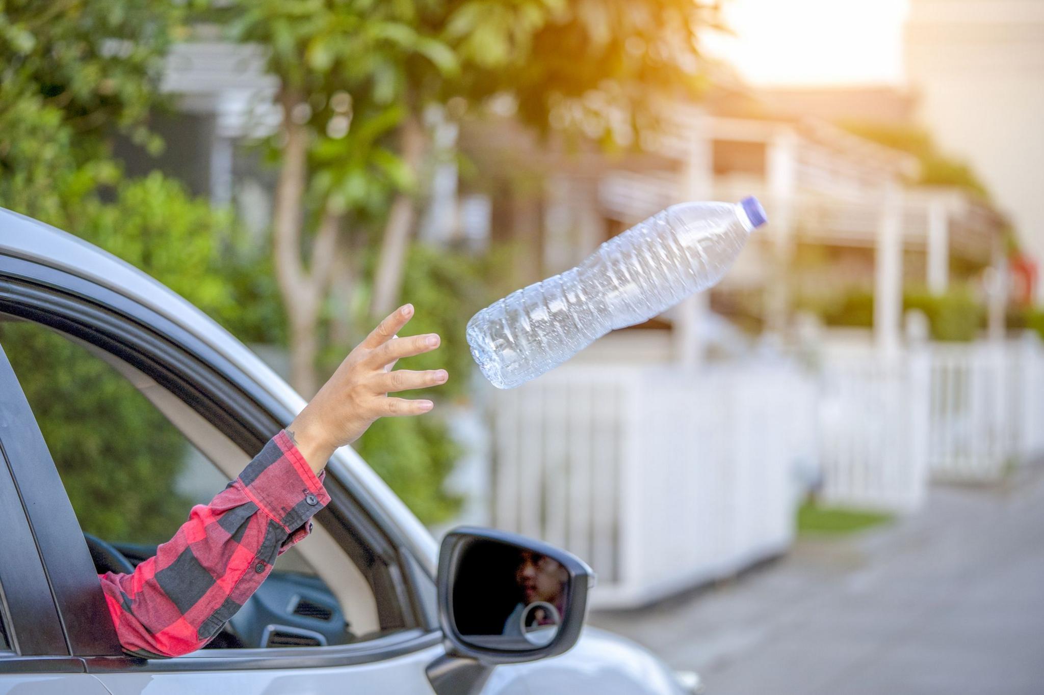 A driver throwing a plastic bottle out of the car