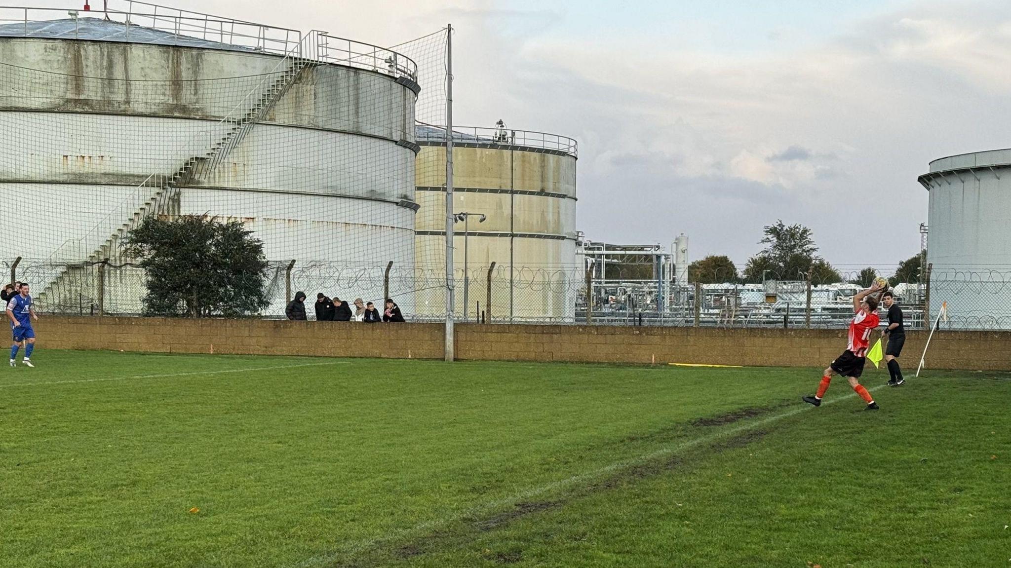 Players on pitch adjacent to petrol depot