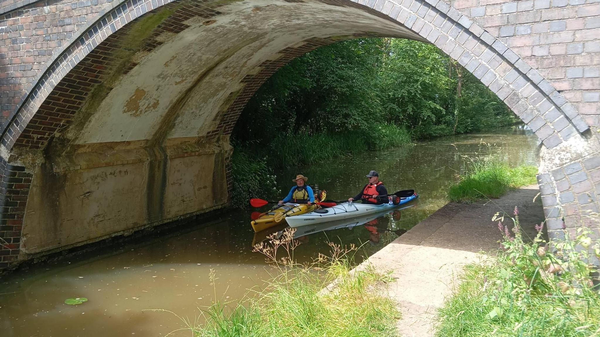 Rob and Paul in kayaks under a bridge