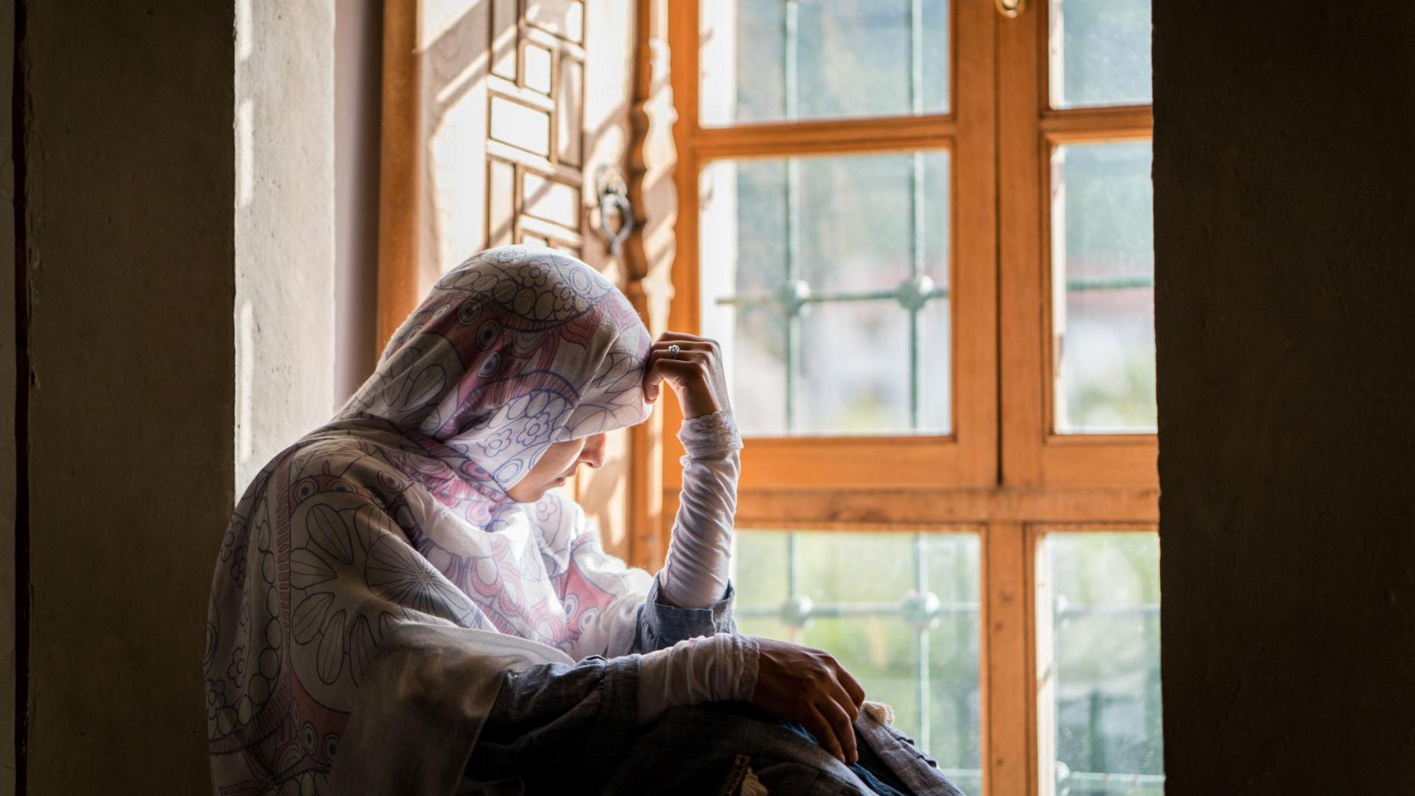 A woman sat in a window bay looking outside