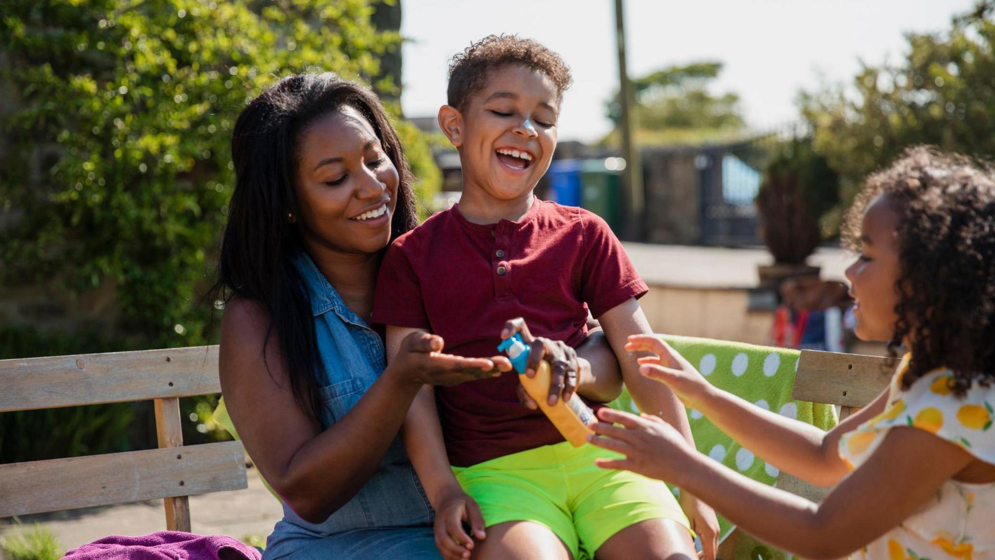 children and their mother apply suncream