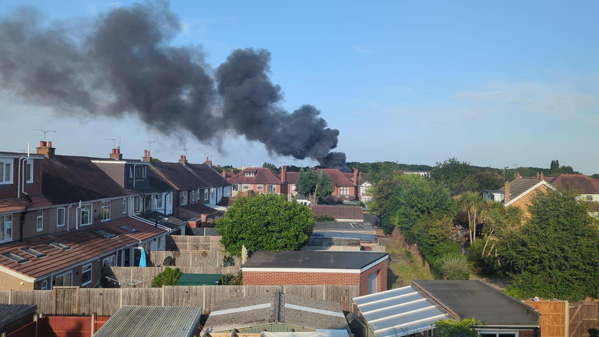 A large plume of smoke above numerous back gardens.