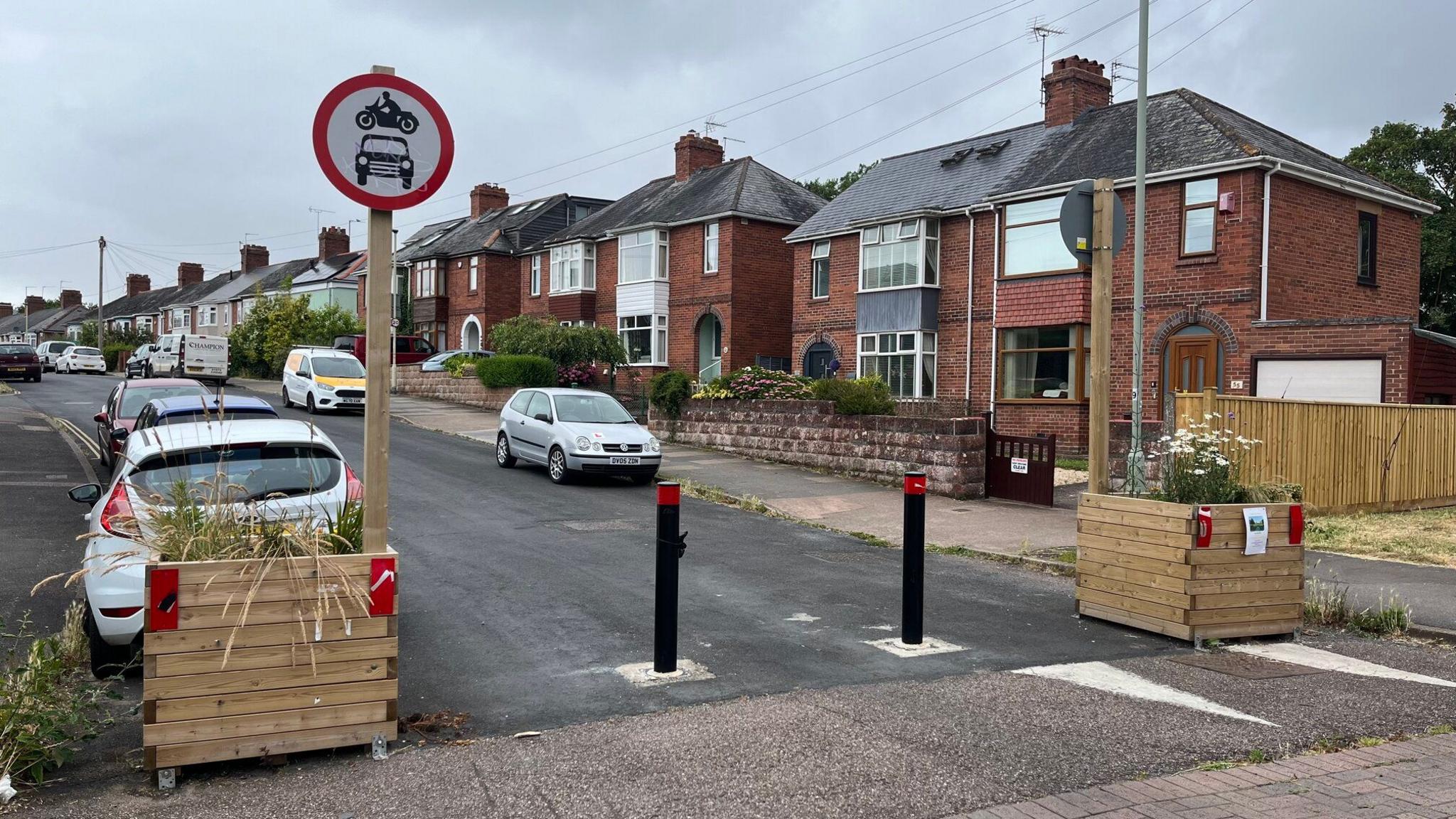 Traffic bollards and a sign prohibiting motorcycles and cars in Hamlin Lane, Exeter