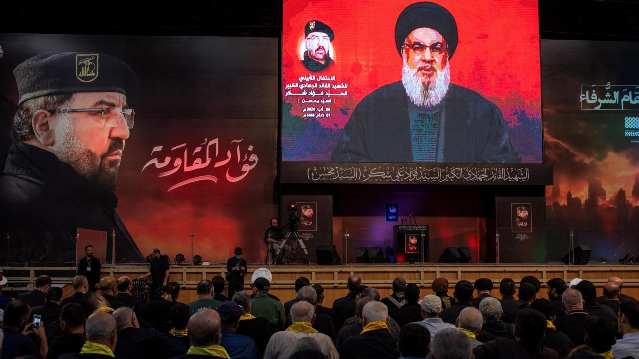 Hezbollah supporters listen to a speech by the group's leader Hassan Nasrallah (right), at a memorial ceremony for senior commander Fuad Shukr (left), after the latter was killed in an Israeli strike (6 August 2024)