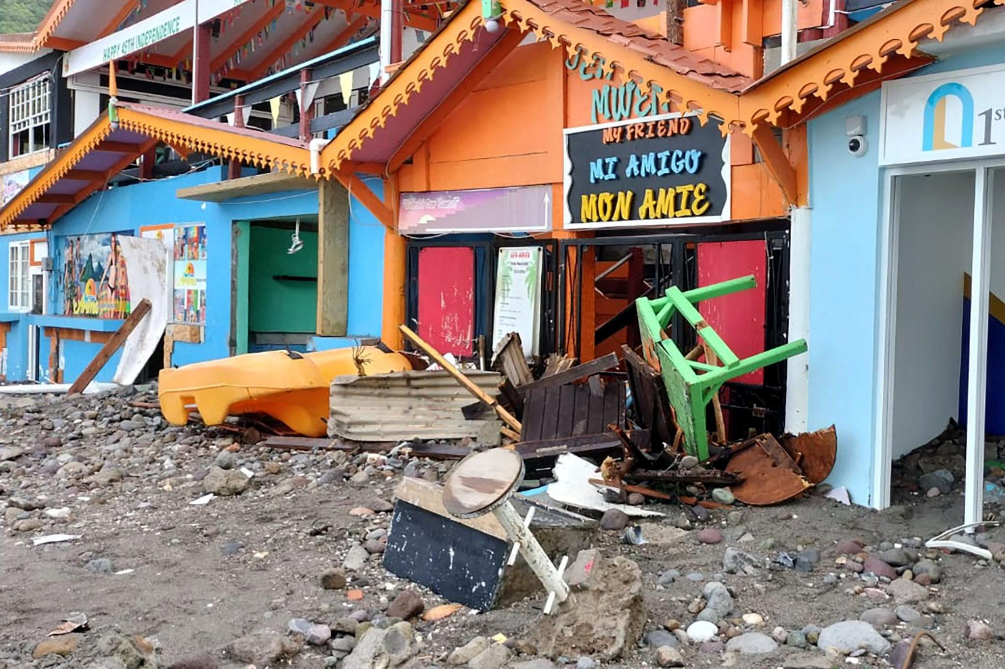 Benches, tables, boats, rocks and sand pile against the doors of waterfront businesses