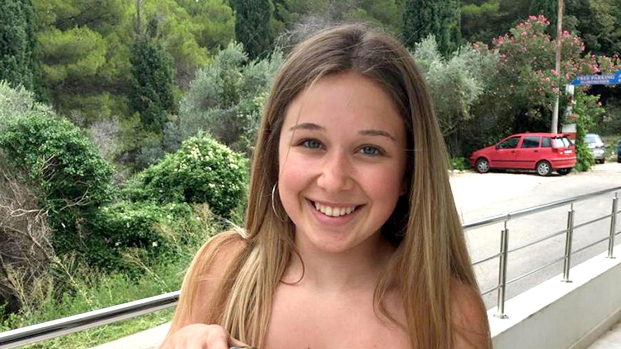 Ellie Gould smiling while stood outside a holiday home with trees in the background.