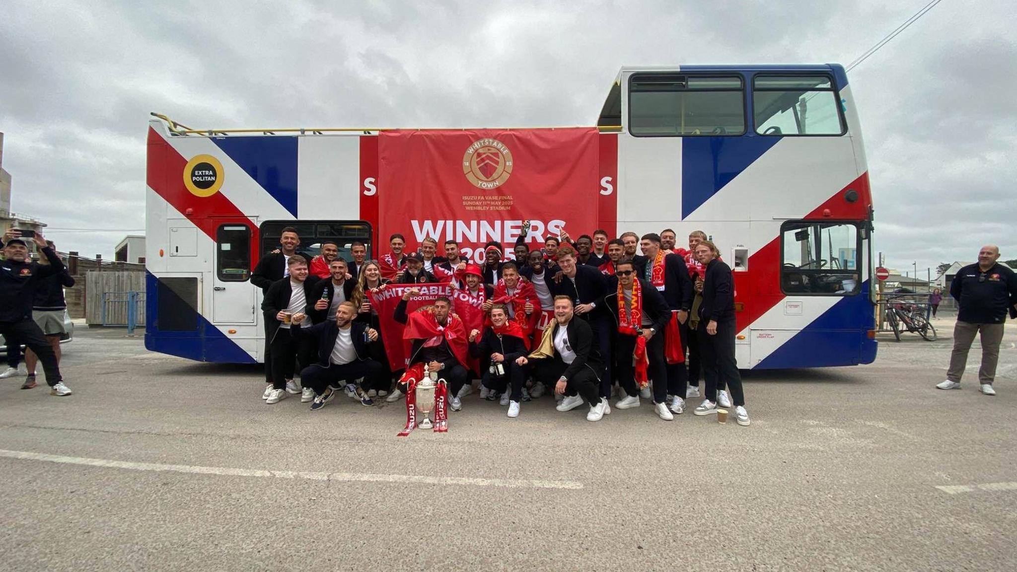 Whitstable Town players in front of an open-top bus in the town's harbour