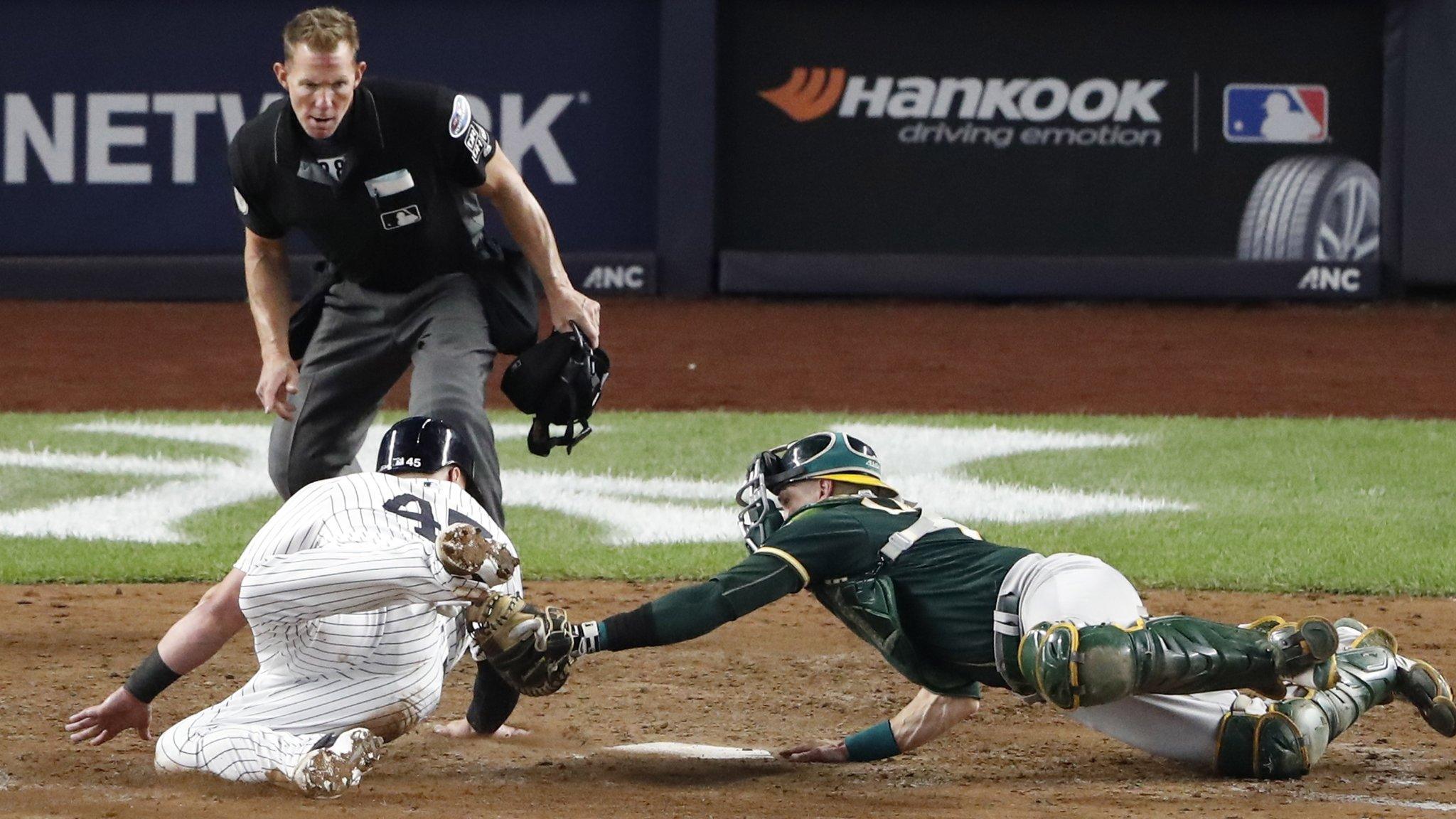 New York, United States, October 3: Luke Voit, left, of the New York Yankees dives into the home plate ahead of Oakland Athletics catcher Jonathan Lucroy to score during their MLB Wildcard playoff game. (Photo by Jason Szenes/EPA)