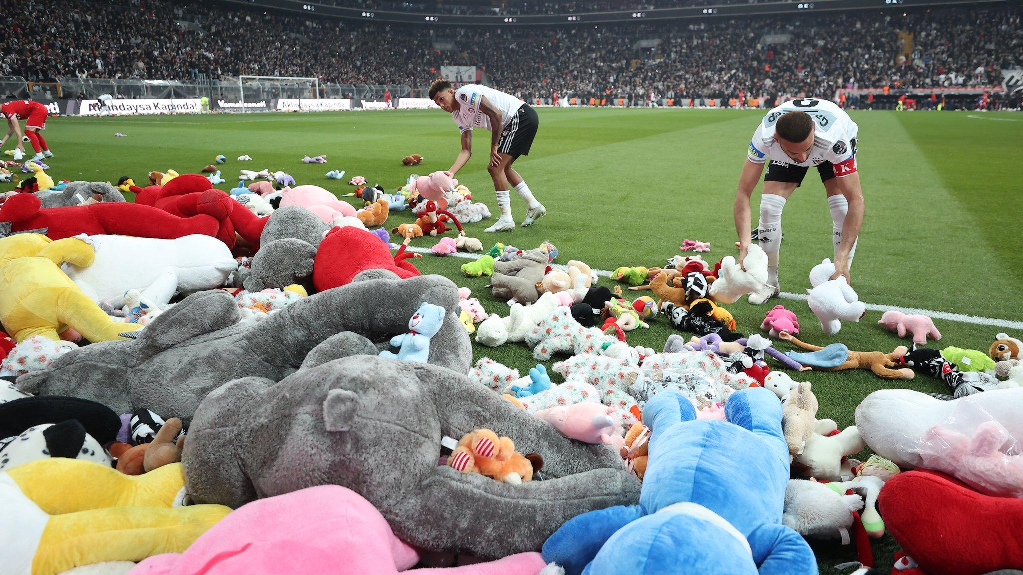 Fans of Besiktas throw Teddy bears onto the field in support for the earthquake victim children