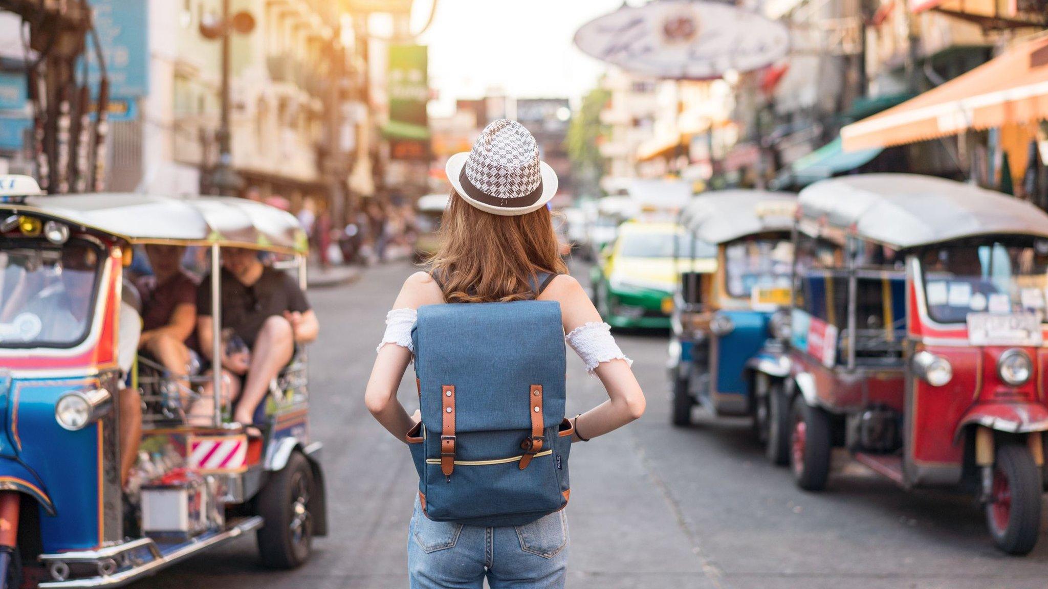 The back of a young woman walking and walking along the pedestrian street in the evening in Bangkok, Thailand, travelers and tourists.