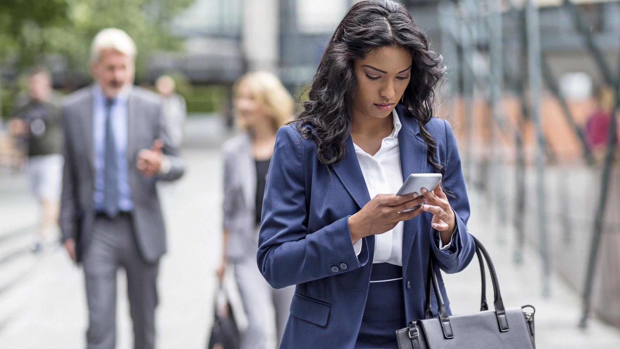 Woman looking at mobile phone while walking