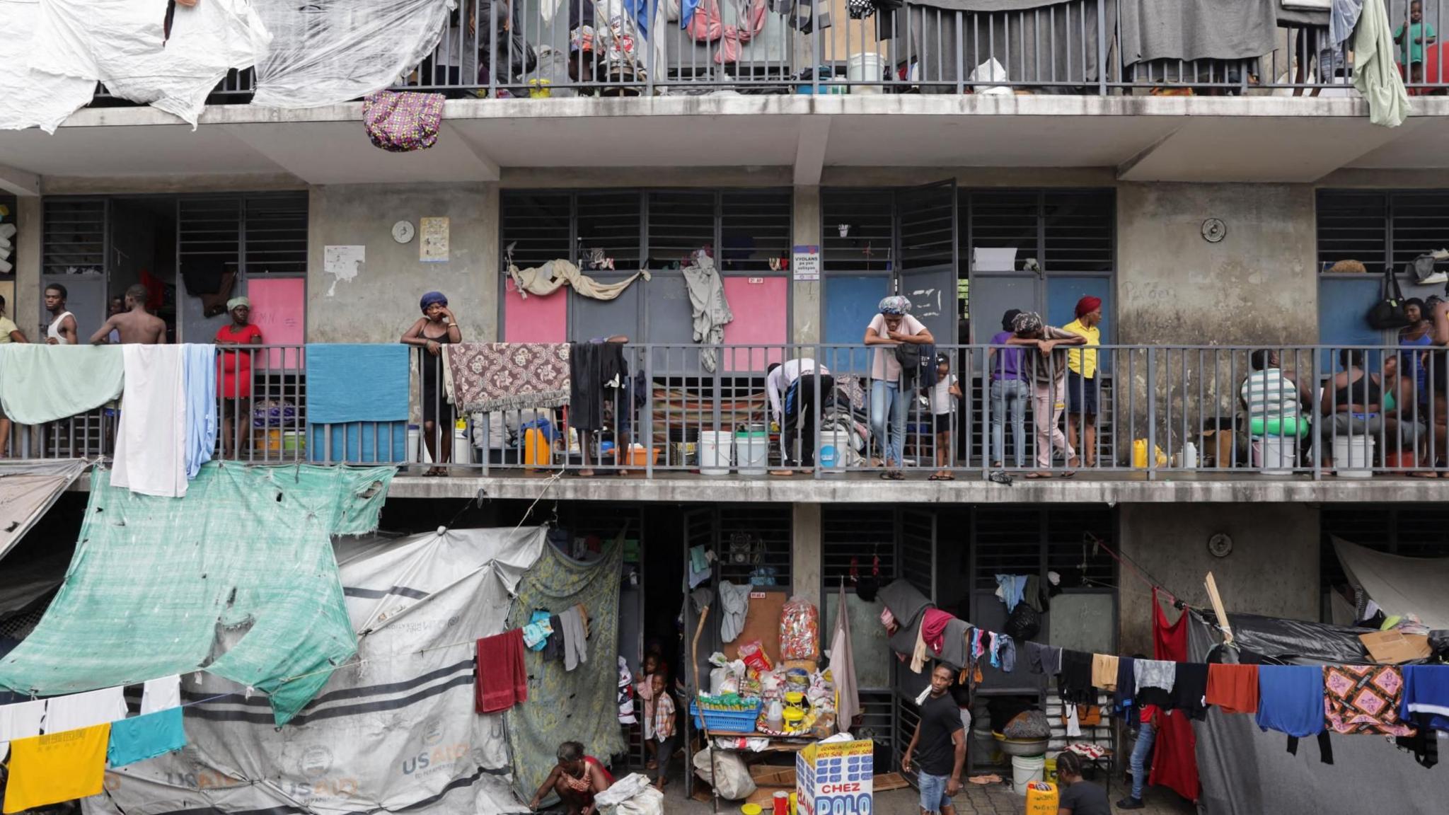A school that is being used as a shelter, with people standing on balconies, washing hanging out and makeshift shelters made from tarpaulins, in Port-au-Prince, October 2025