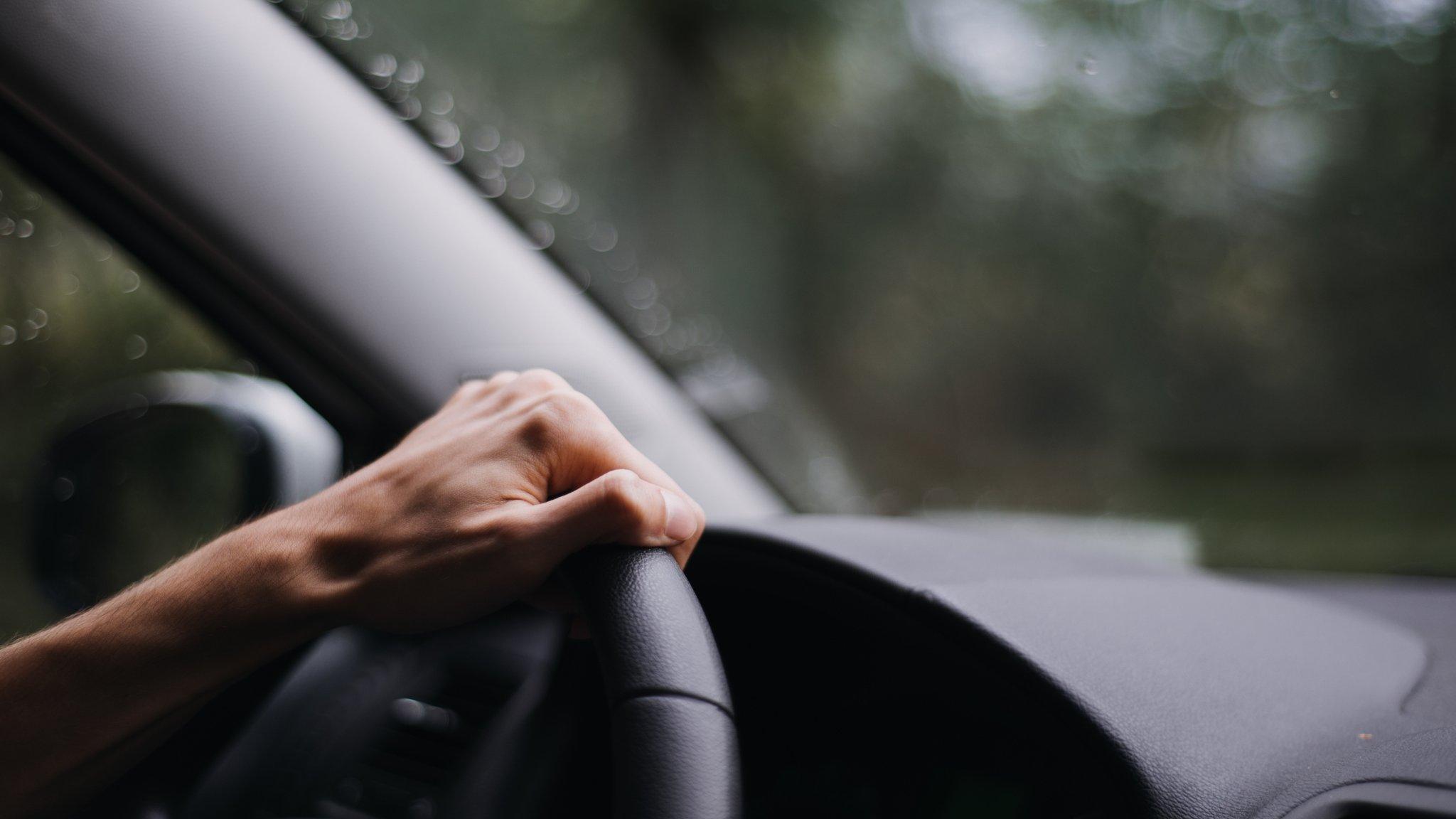 A person's hand on a steering wheel