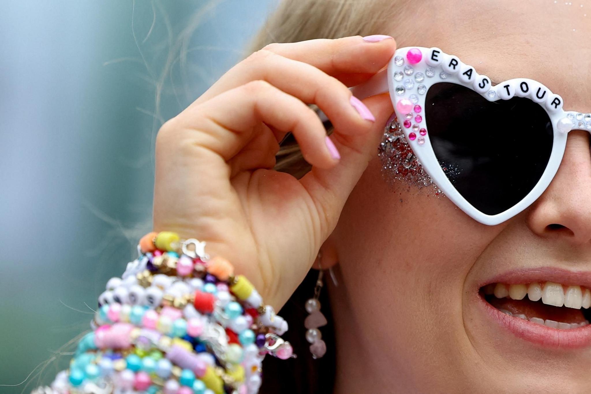 A fan wearing Taylor Swift Eras sunglasses 
