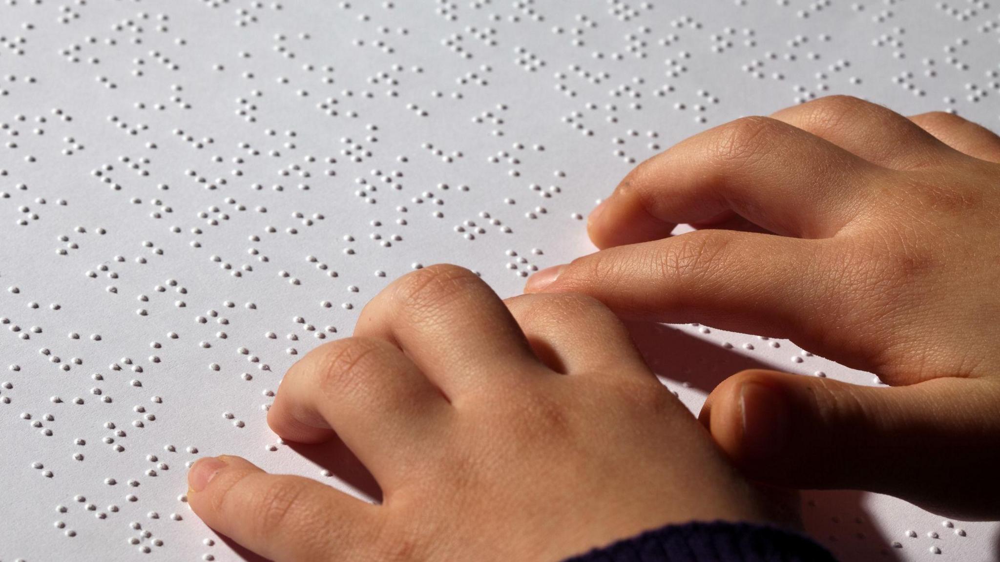 a child's hands reading a braille book
