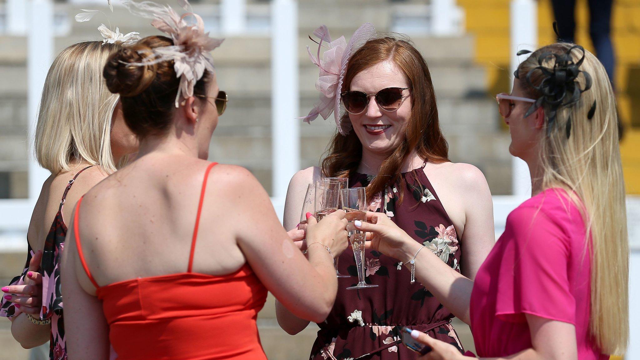 Racegoers enjoy a drink in the sun before the first race at Haydock Park Racecourse, Merseyside