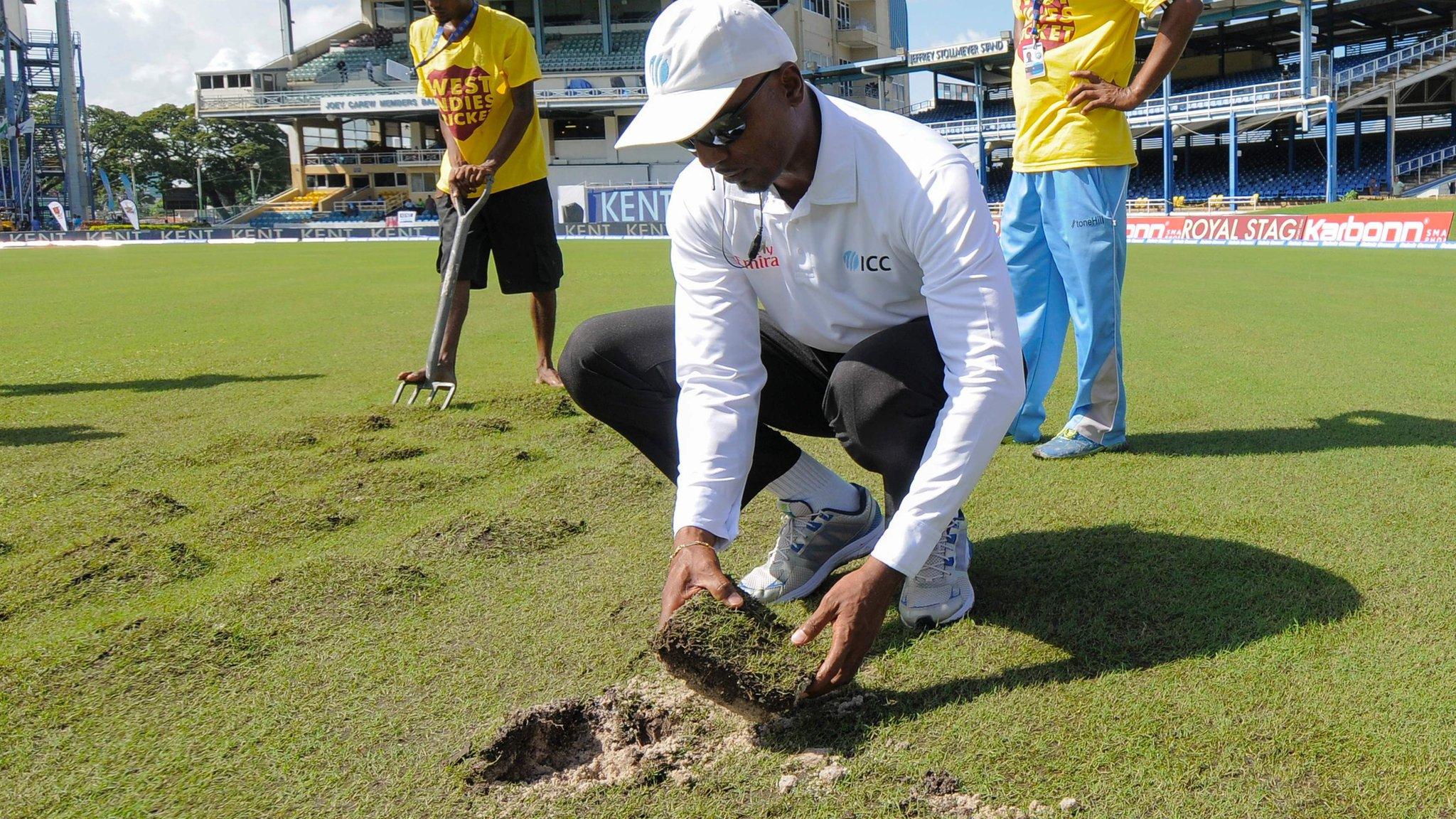 Umpire Gregory Brathwaite inspects the damaged outfield in Trinidad