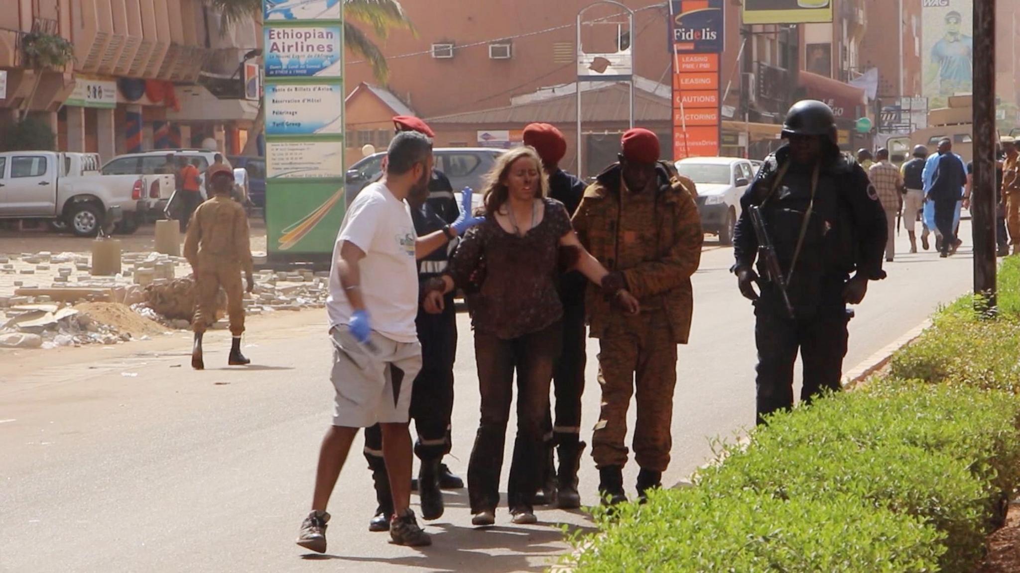 A woman being led to safety in Ouagadougou, Burkina Faso, Saturday Jan. 16, 2016