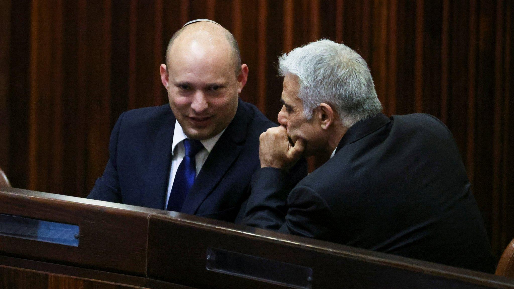 Israeli politicians Naftali Bennett (L) and Yair Lapid (R) talk during a parliamentary session in Jerusalem (2 June 2021)