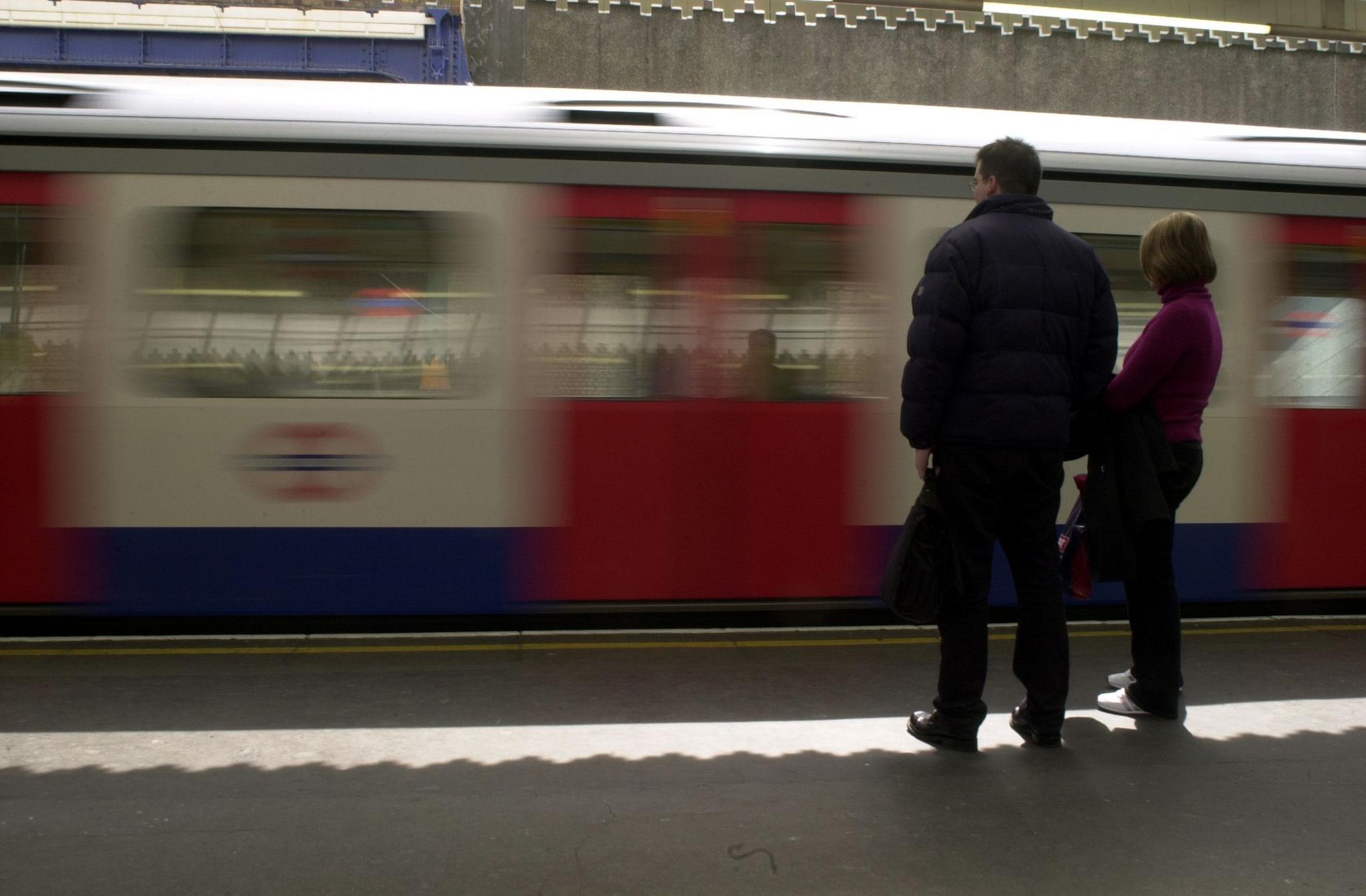 London Underground Tube train arrives at platform with passengers waiting. Slight blur effect