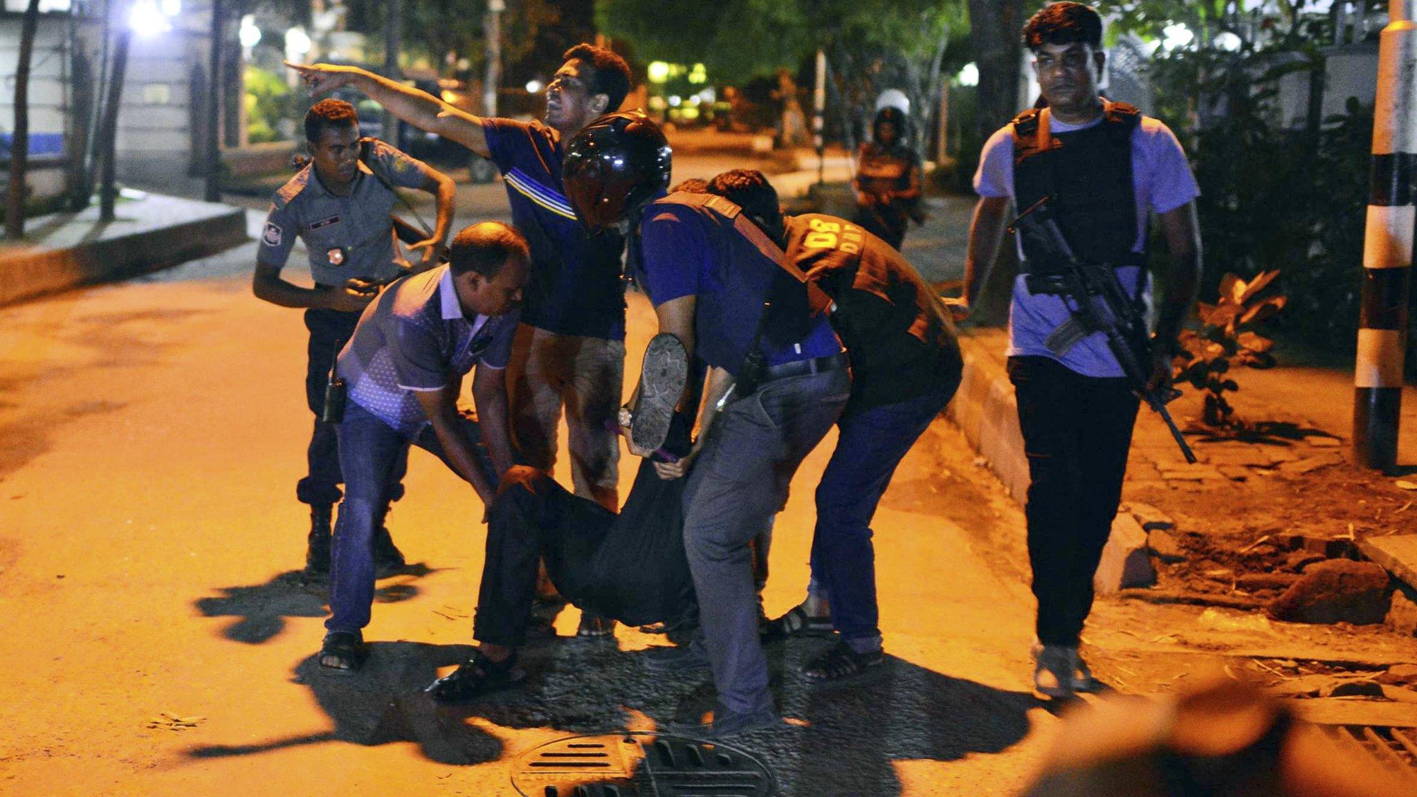 People help injured person after gunmen attack restaurant in Dhaka, Bangladesh, Friday, July 1, 2016