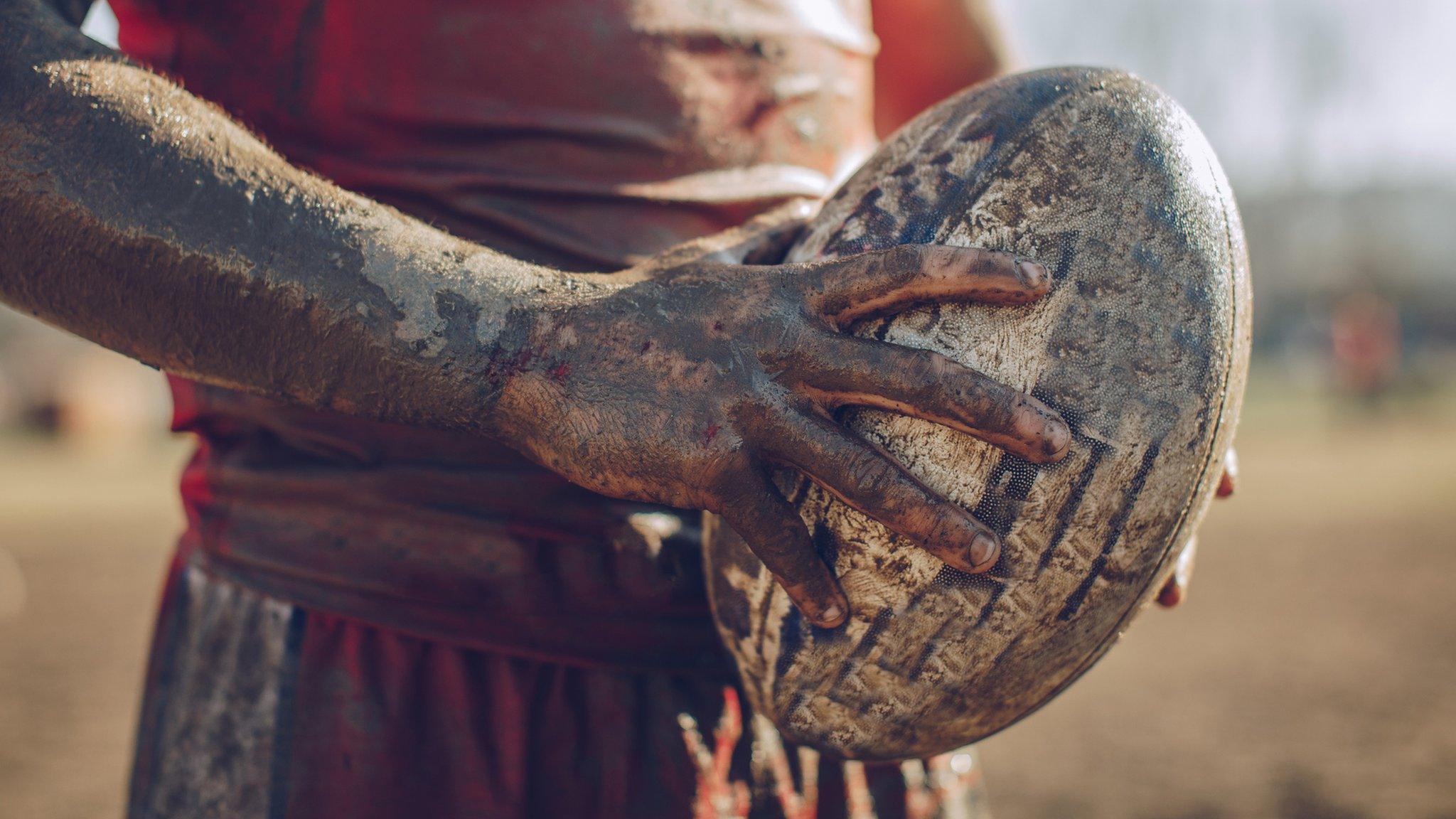 Muddy player and rugby ball.