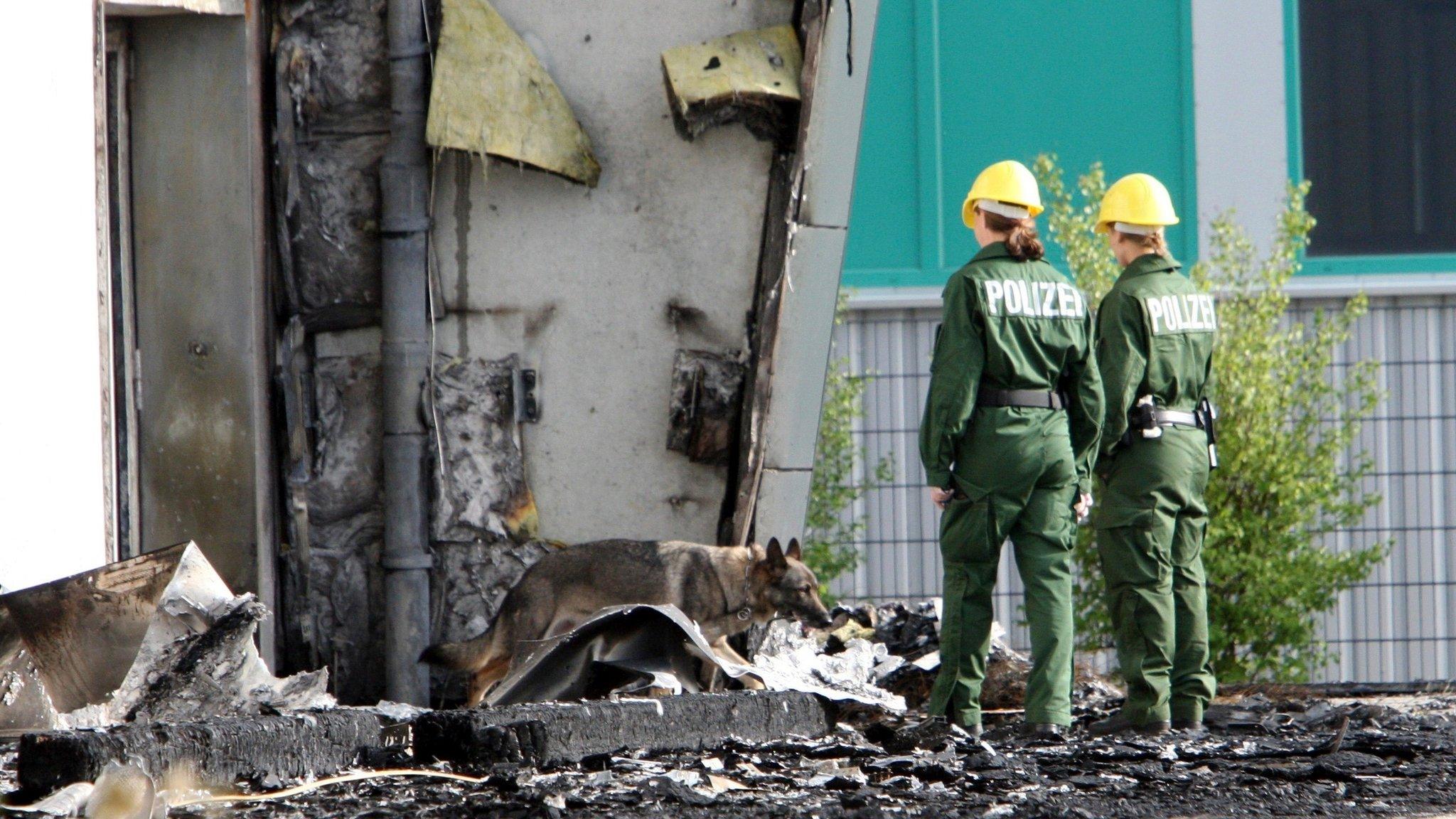 In this Aug. 26, 2015 file picture police officers and their sniffer dog examine the ruins of a burned out gym in Nauen, Germany