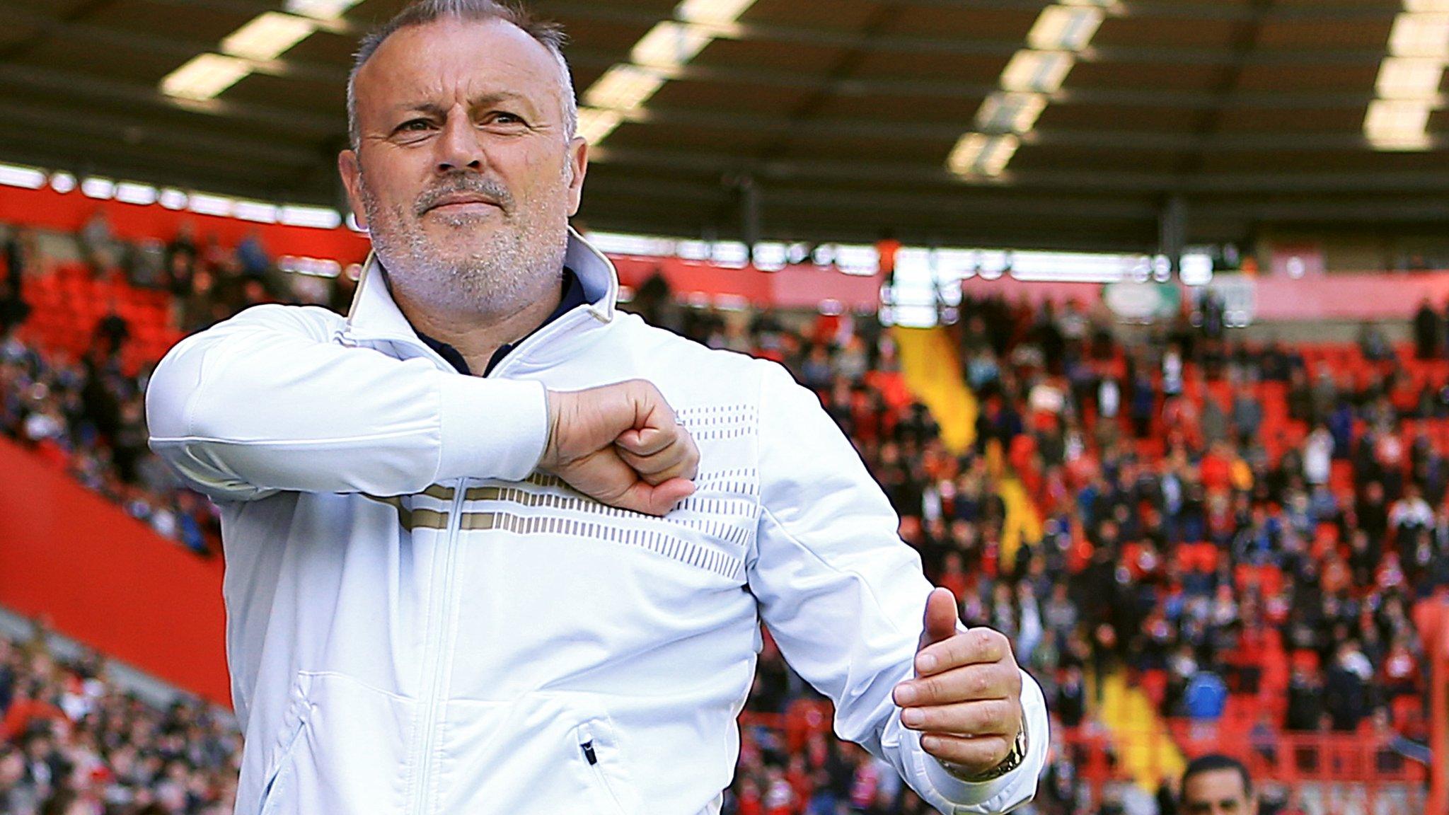 Neil Redfearn hits the Leeds United badge on his shirt as he acknowledges fans while he was manager of the club