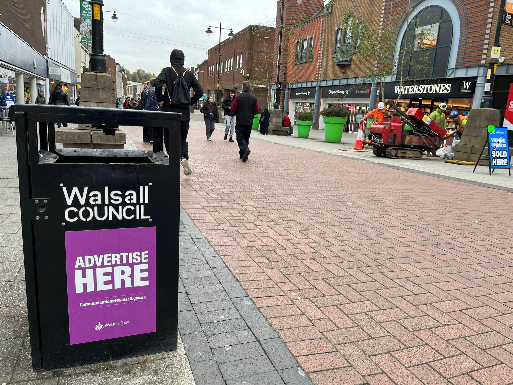 A bin in Walsall town centre with a purple "Advertise Here" sticker on it.