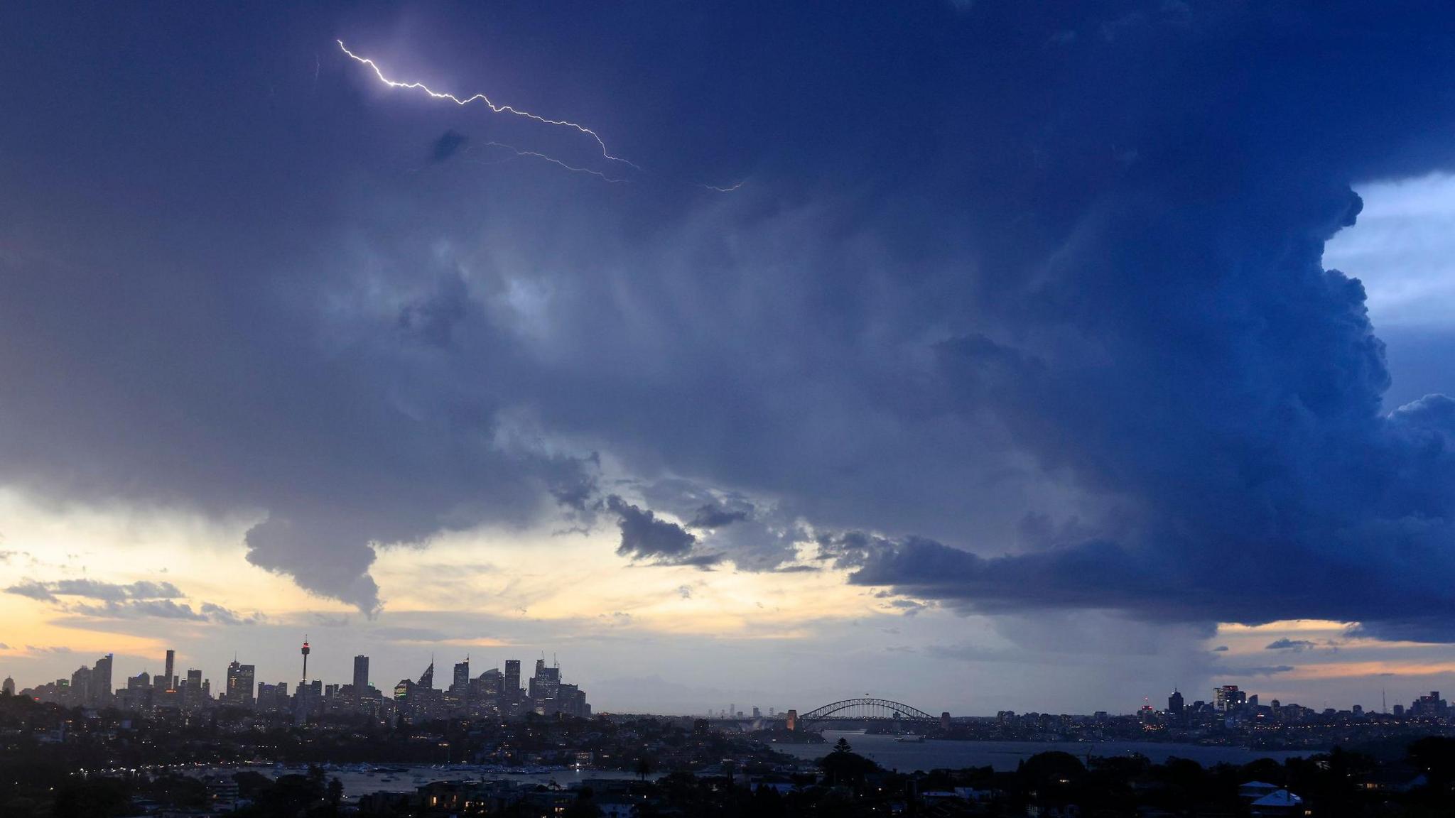 Lightning is seen over the city skyline as storm clouds gather