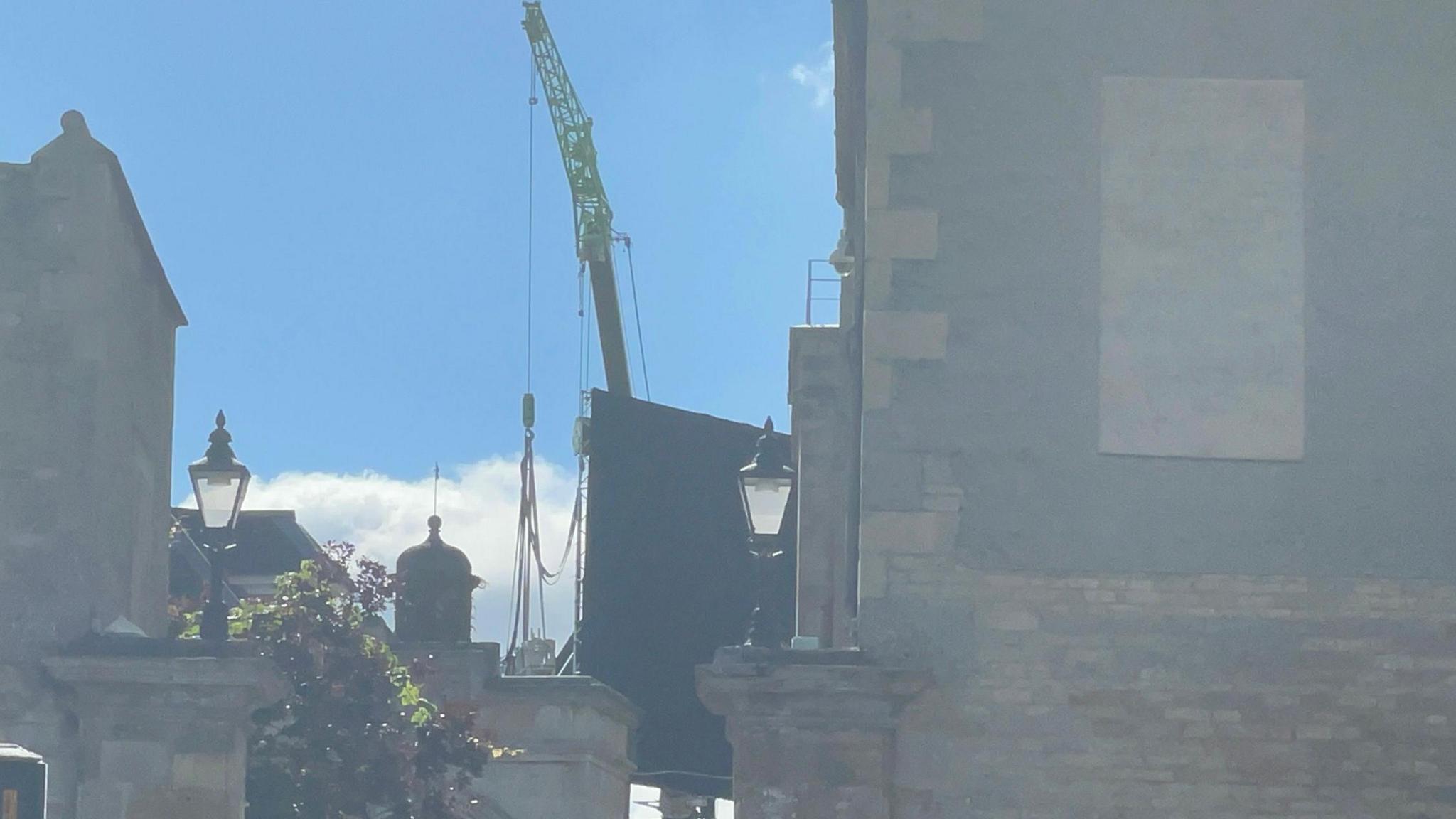 A large blackboard hanging from a crane in front of windows at Burghley House