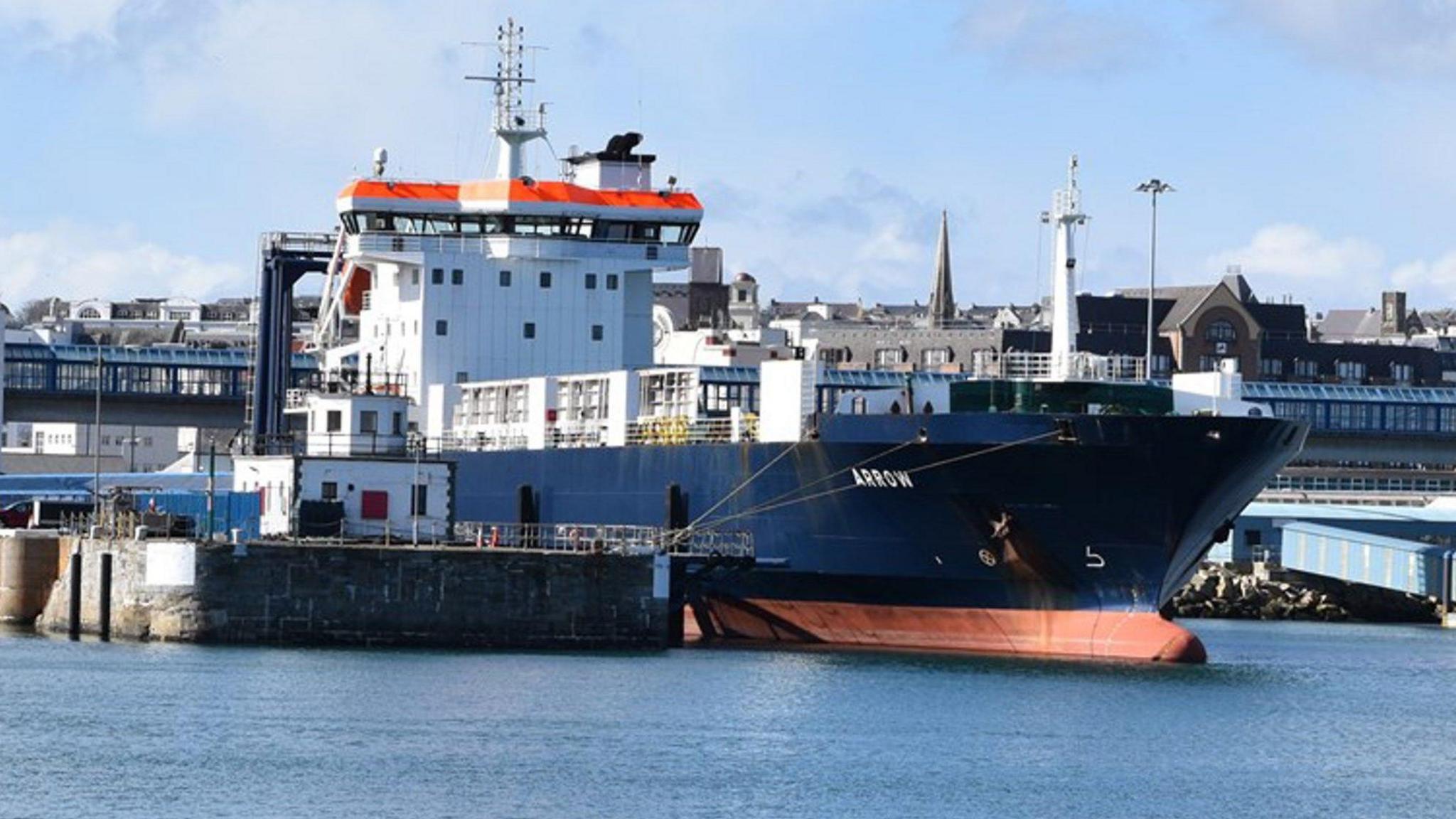 Arrow pictured docked. It has a dark blue hull with ARROW written on the side in white writing. The crew cabin, bridge and flying bride is all white with an orange roof. 