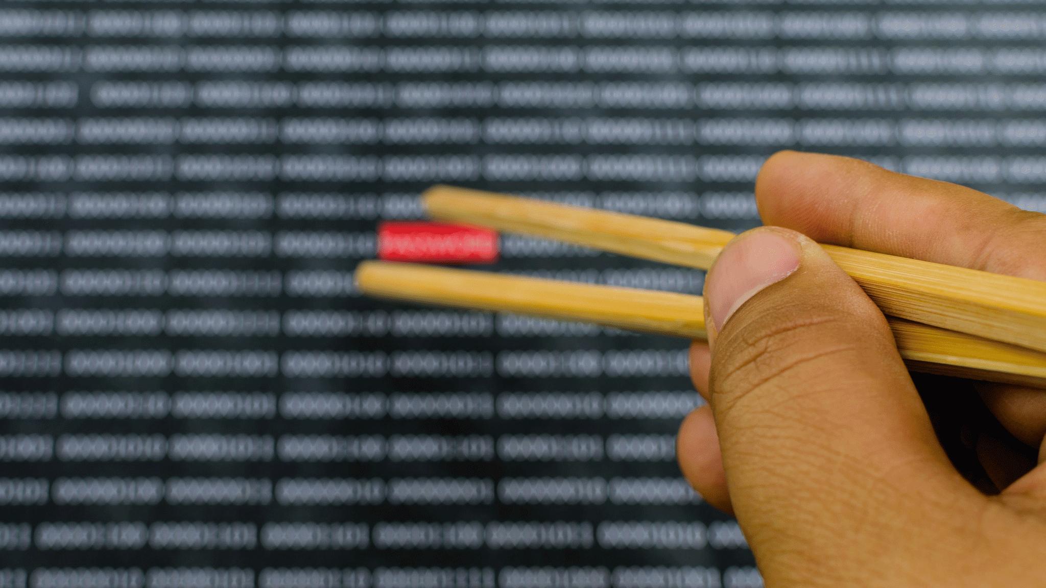 Man with chopsticks picking up small object