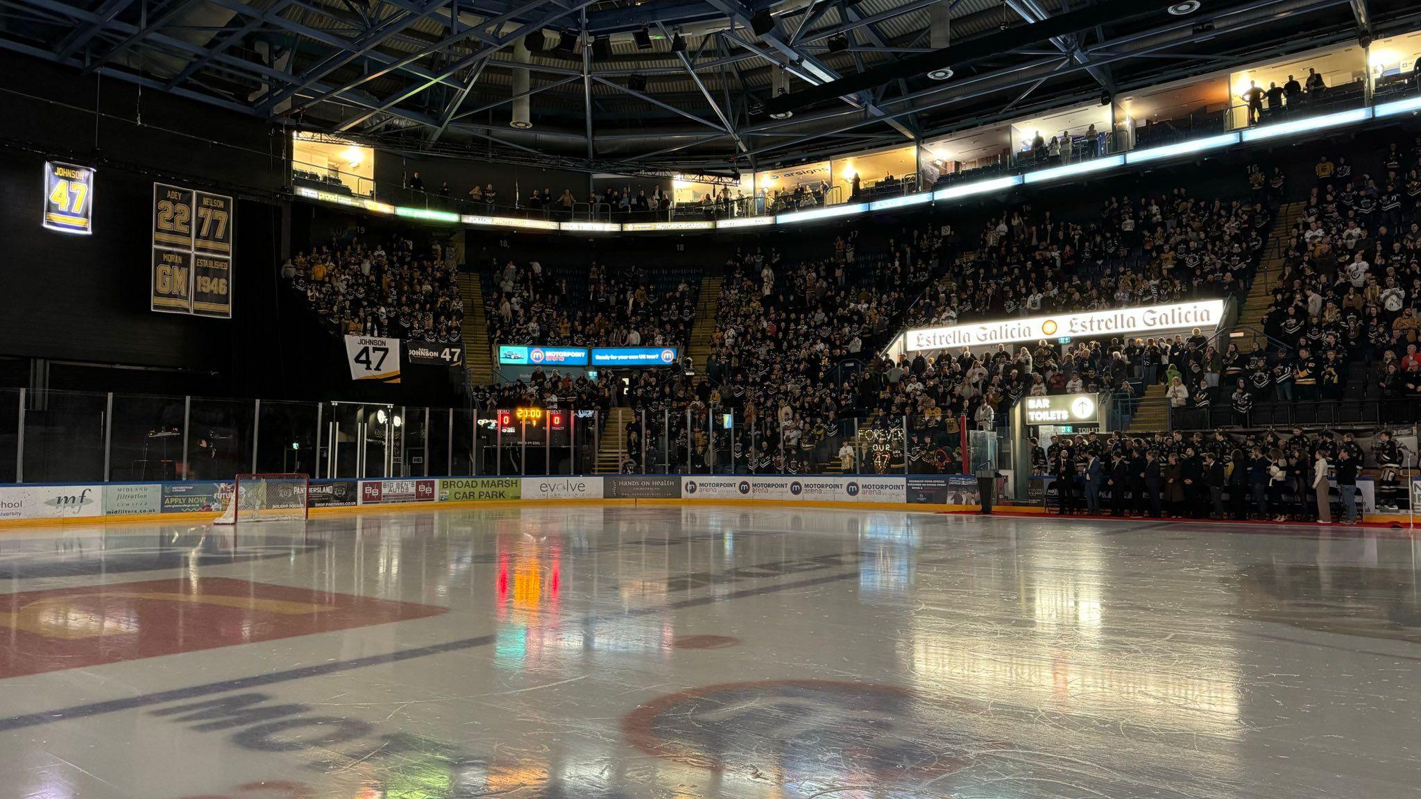 Spectators in their seats with ice rink in the foreground at a ceremony to remember Adam Johnson