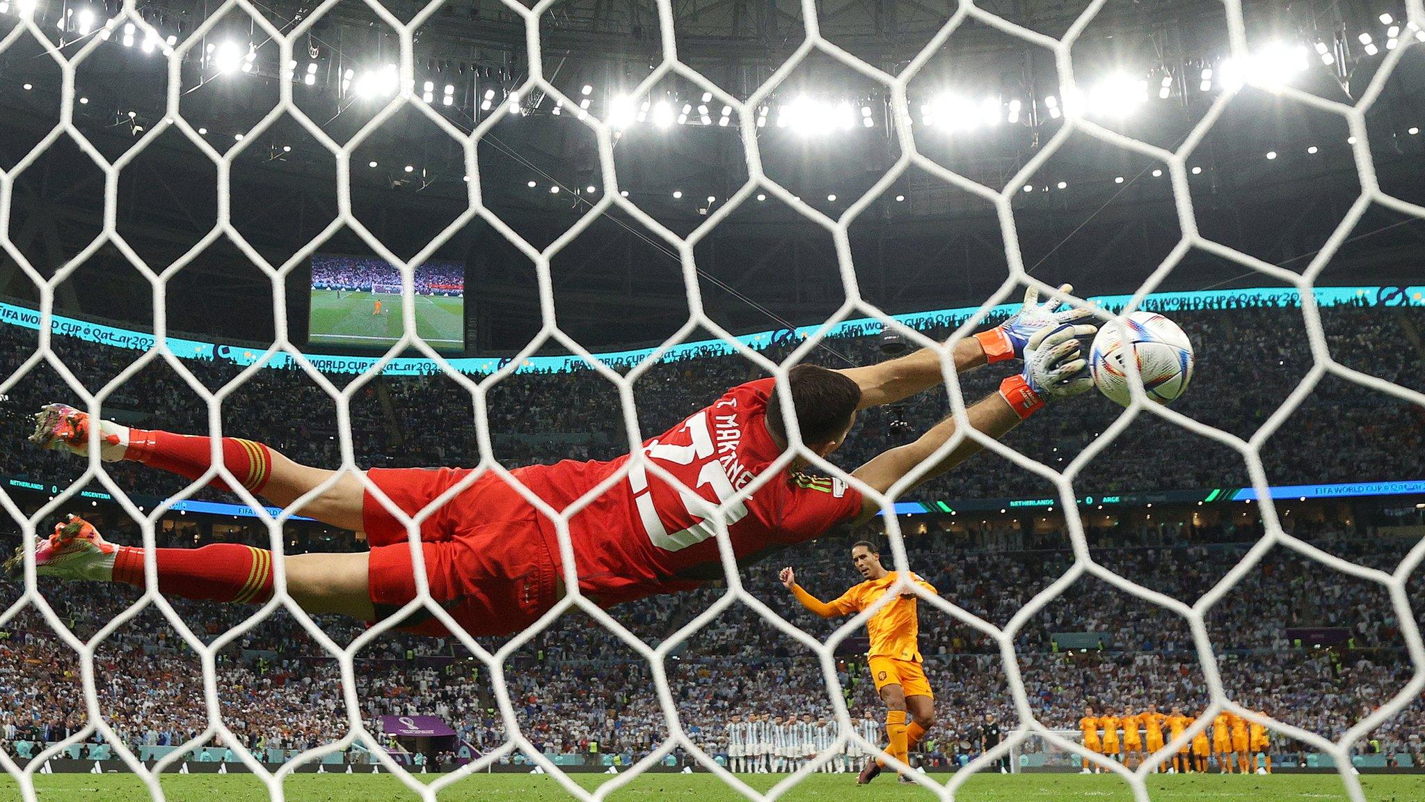 A shot from behind the goal as Emiliano Martinez dives at full stretch to save Virgil van Dijk's penalty