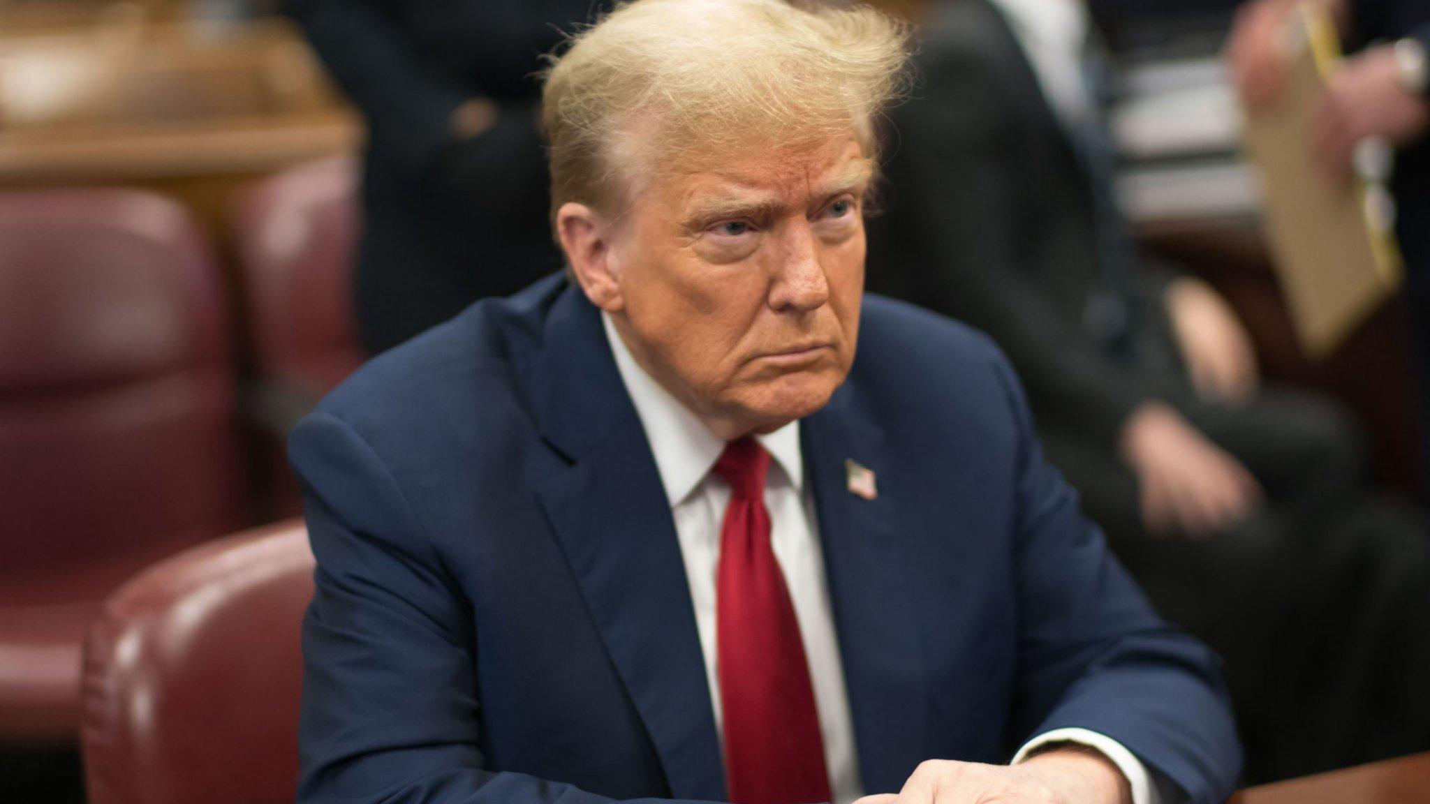 Donal Trump sits at a table in a court room in NY