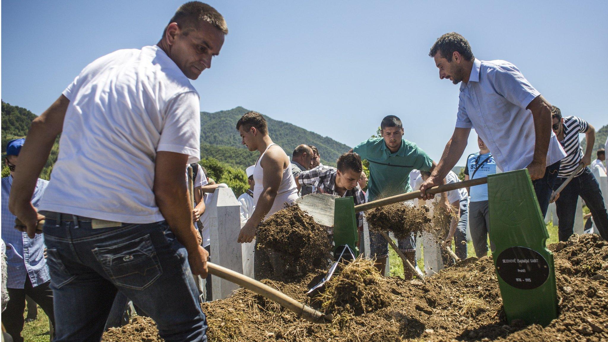 Family members and volunteers bury one of the 136 coffins of newly-identified victims of the 1995 Srebrenica massacre into its final grave mass funeral during the 20th anniversary of the massacre at the Potocari cemetery and memorial on July 11, 2015 in Srebrenica