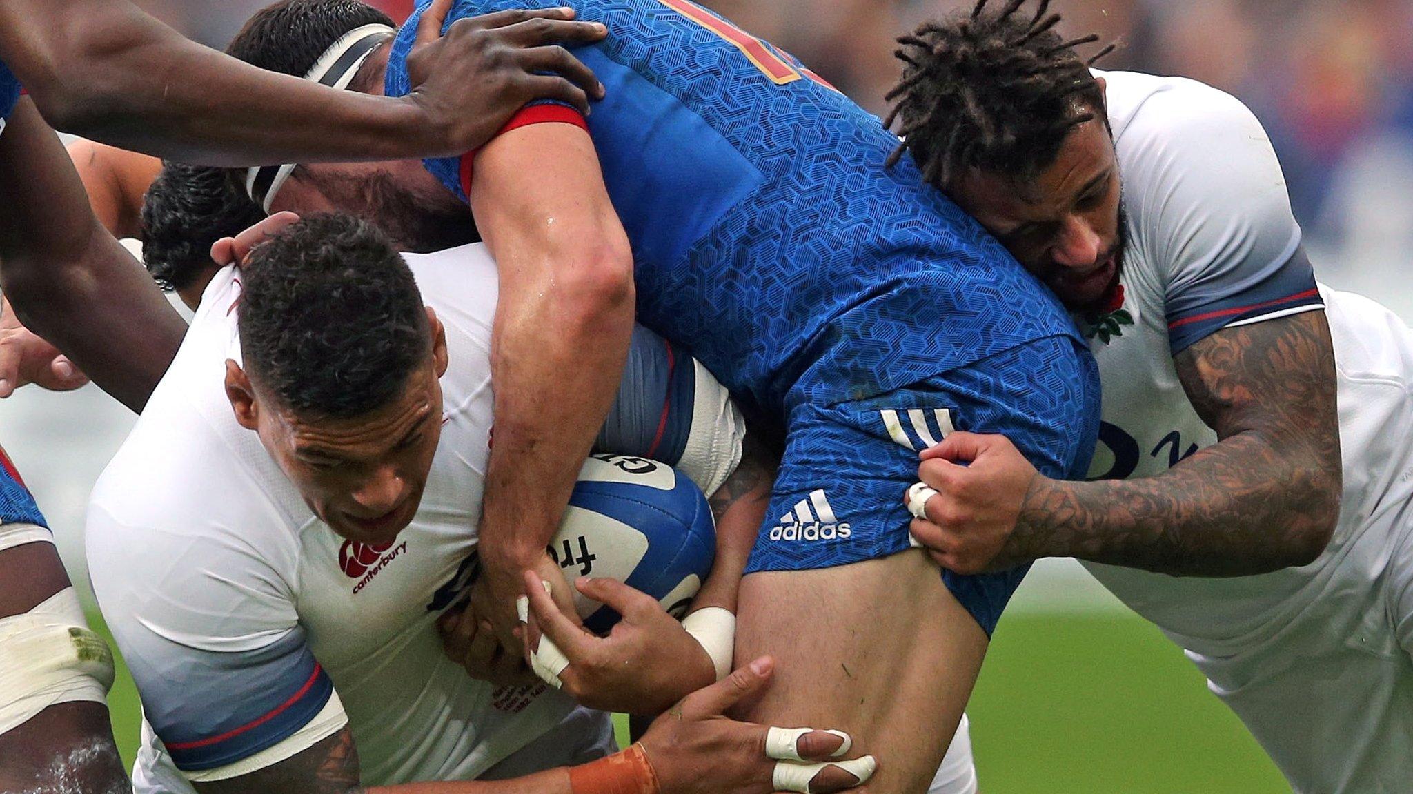 England back rowers Nathan Hughes and Courtney Lawes combine to tackle a France forward on Saturday