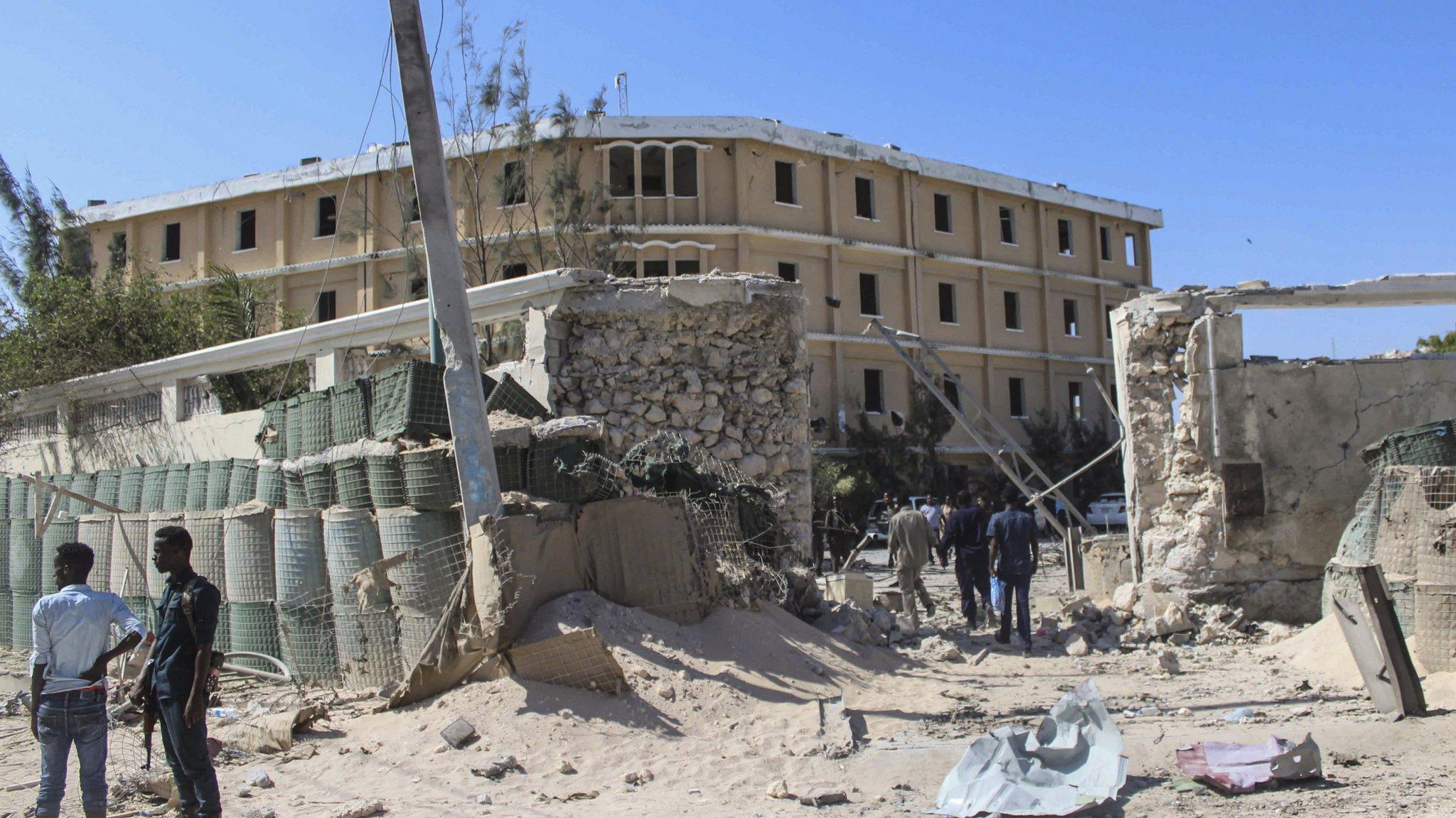 Somali security officers stand at the scene of a gun fight where security forces battled al-Shabab fighters who stormed the government building after exploding a car bomb in central Mogadishu