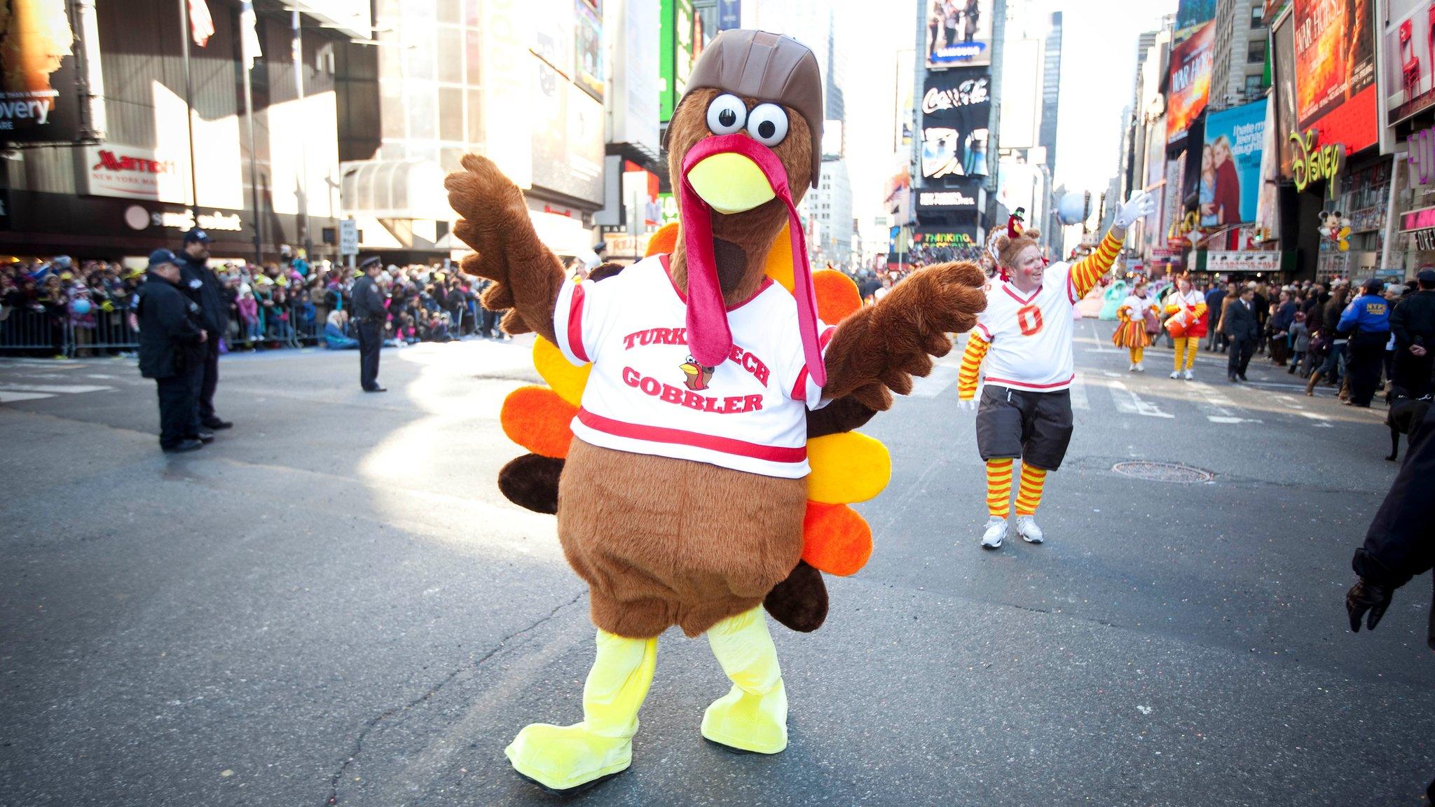 A person dressed as a turkey waves in the Thanskgiving Day parade