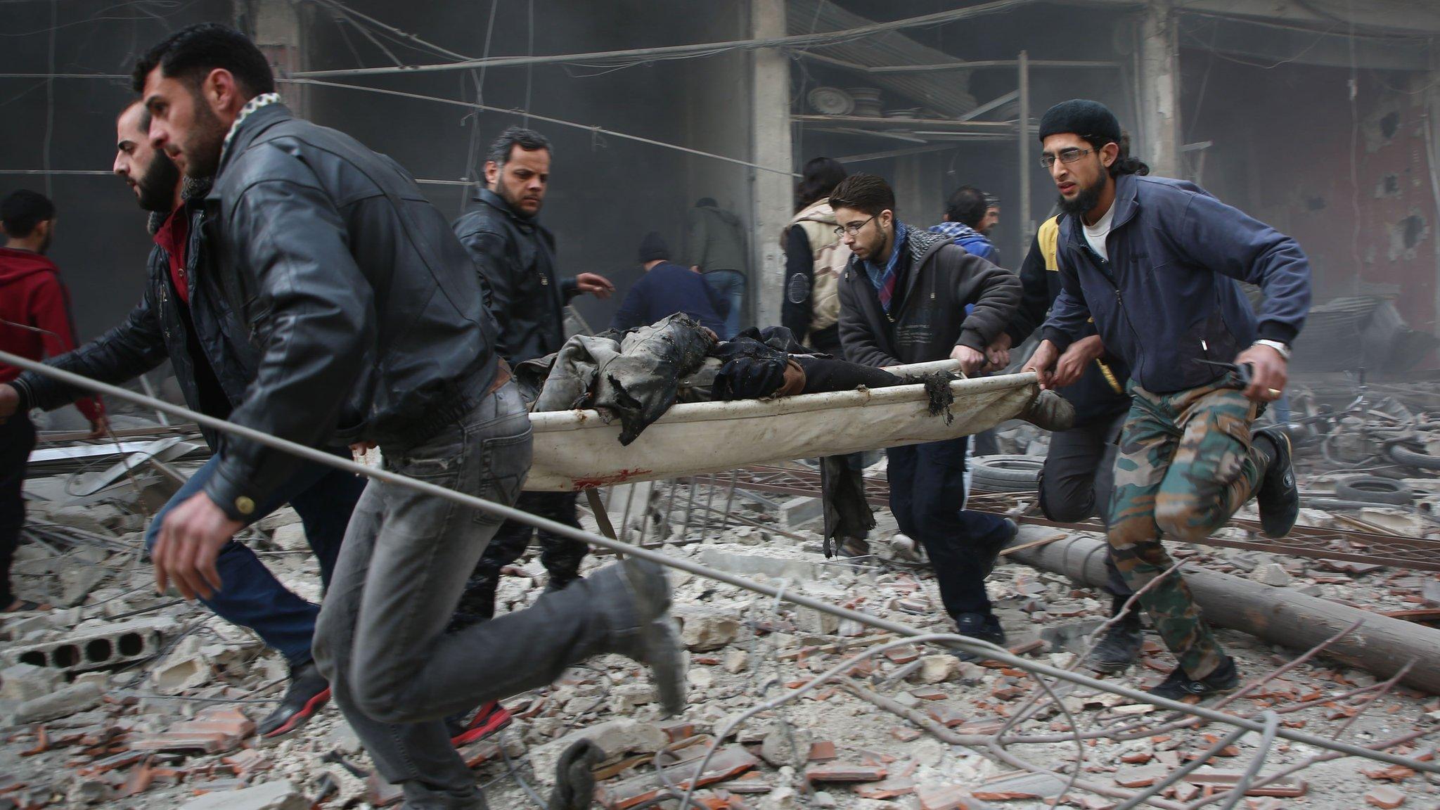 Rescuers carry a badly injured man in a stretcher after a reported air strike on the town of Kafr Batna, in the Eastern Ghouta area outside Damascus (6 February 2018)