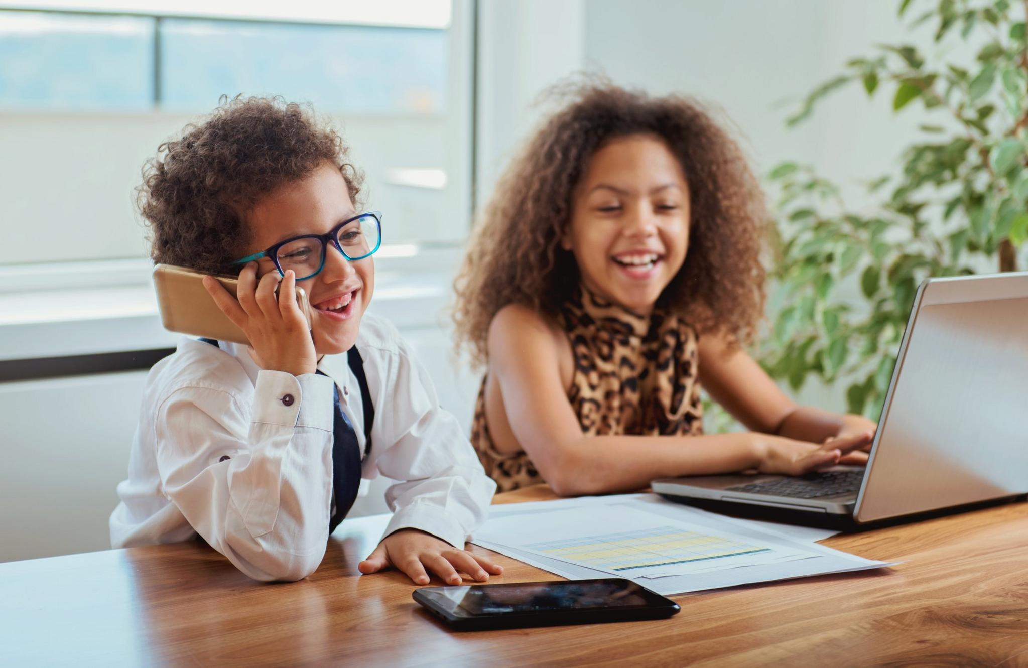 two-children-at-a-desk-laughing-and-working