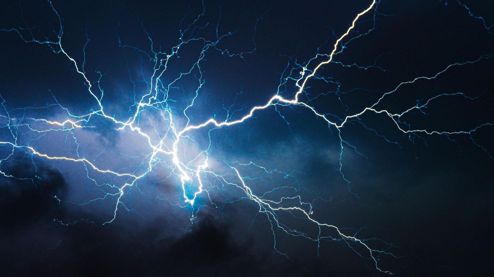 A lightning bolt of blue and white exploded on to a dark blue night sky.