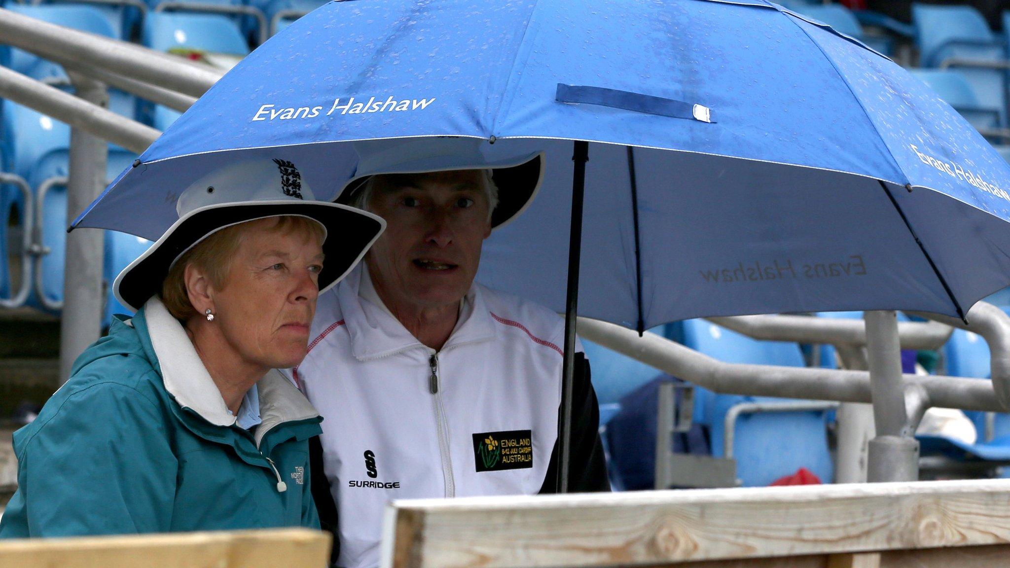 Spectators shelter under an umbrella