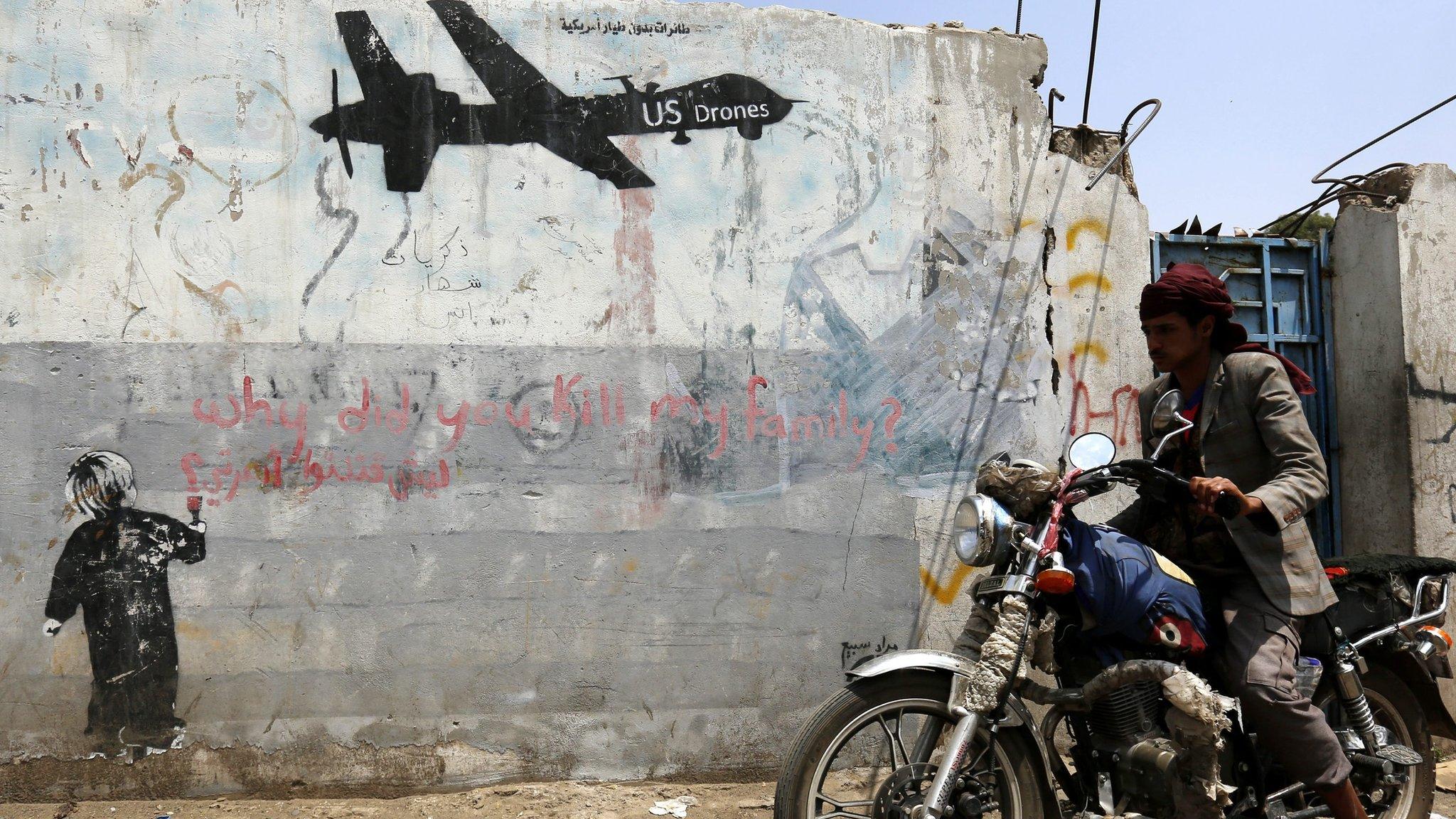 Yemeni rides motorcycle past graffiti protesting against US drone operations in Yemen. 5 September 2016