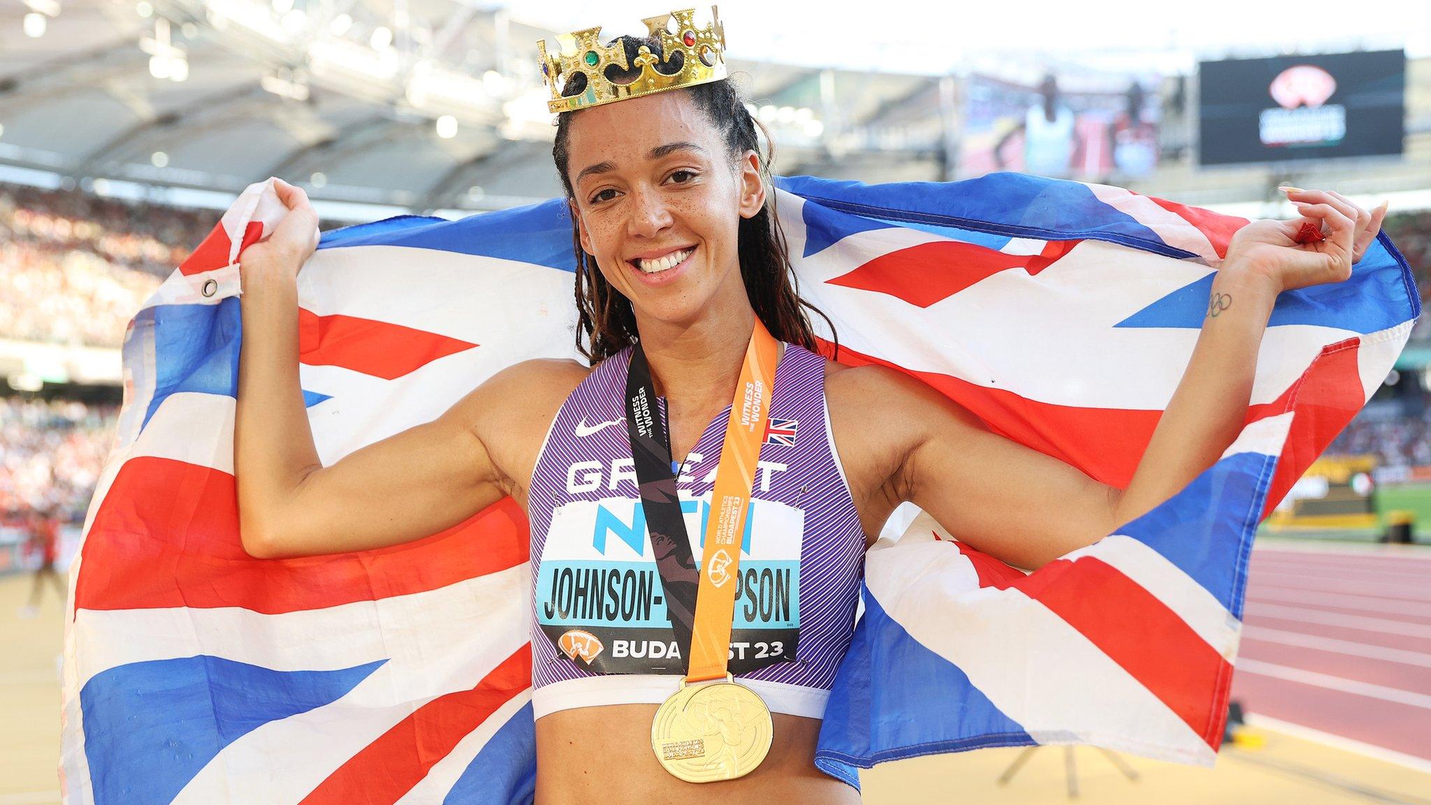 Katarina Johnson-Thompson wearing a crown, her medal and holding up a British flag after winning world gold