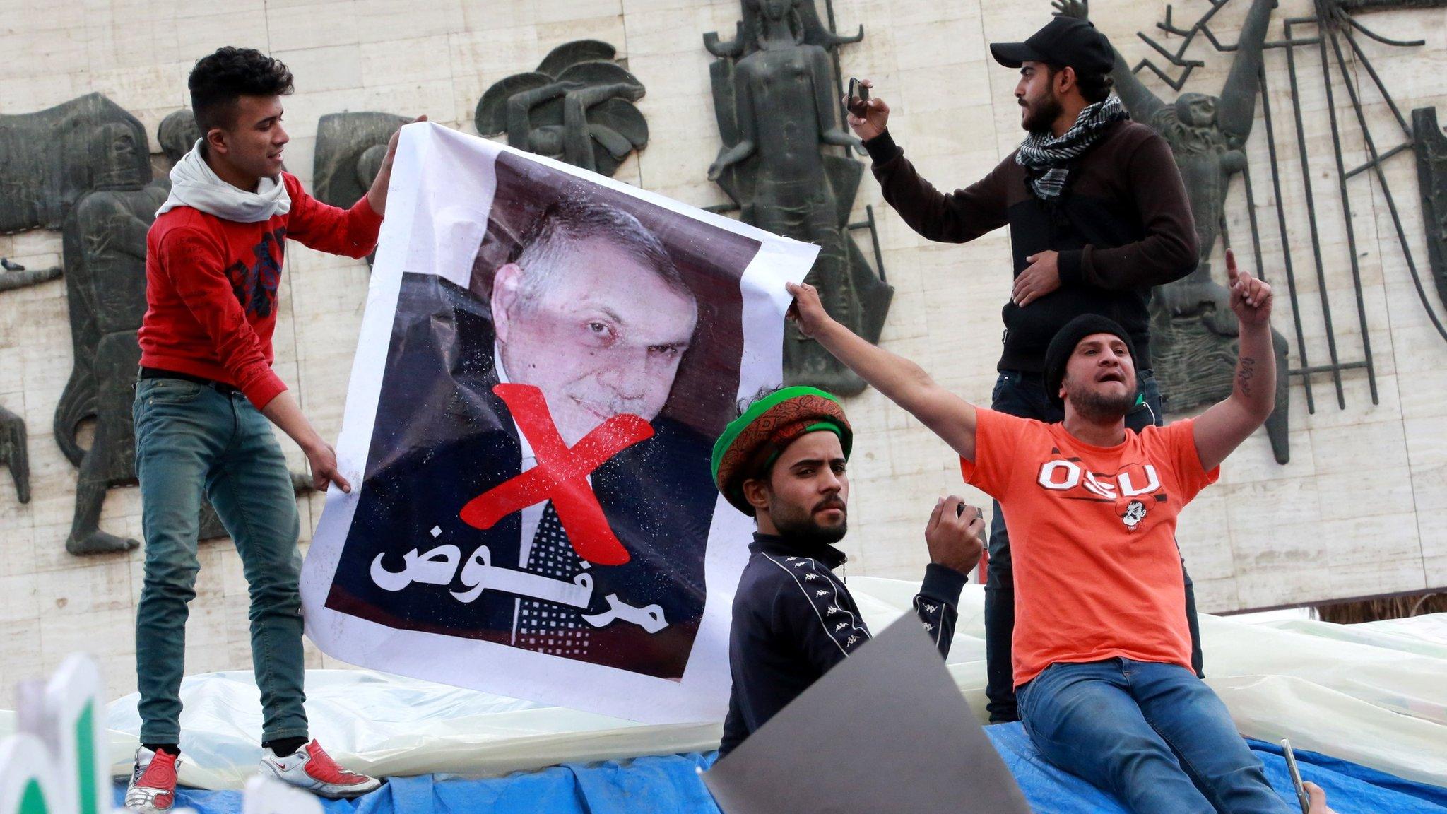 Iraqi hold up a poster showing former Prime Minister-designate Mohammed Allawi and the word "rejected" in Tahrir Square, Baghdad (1 March 2020)